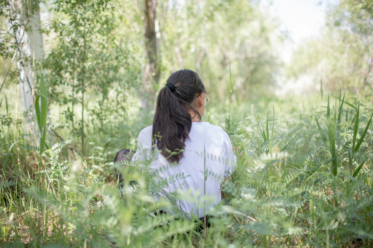 A child sits in a park with her back turned