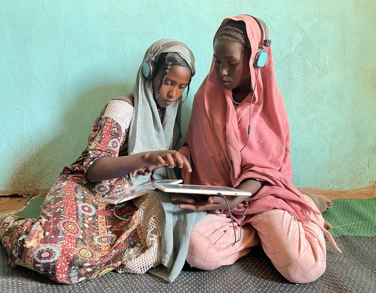 Education- Amal (13, left) and Sarah (13, right) play educational games on their solar-powered tablet in the UNICEF-supported e-learning center in Jabalain, White Nile state, Sudan