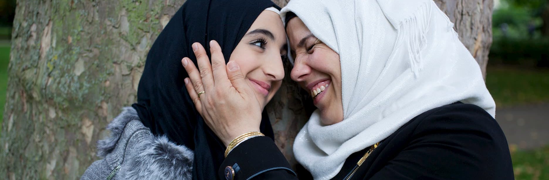 A mother holding the face of her daughter and smiling at eachother