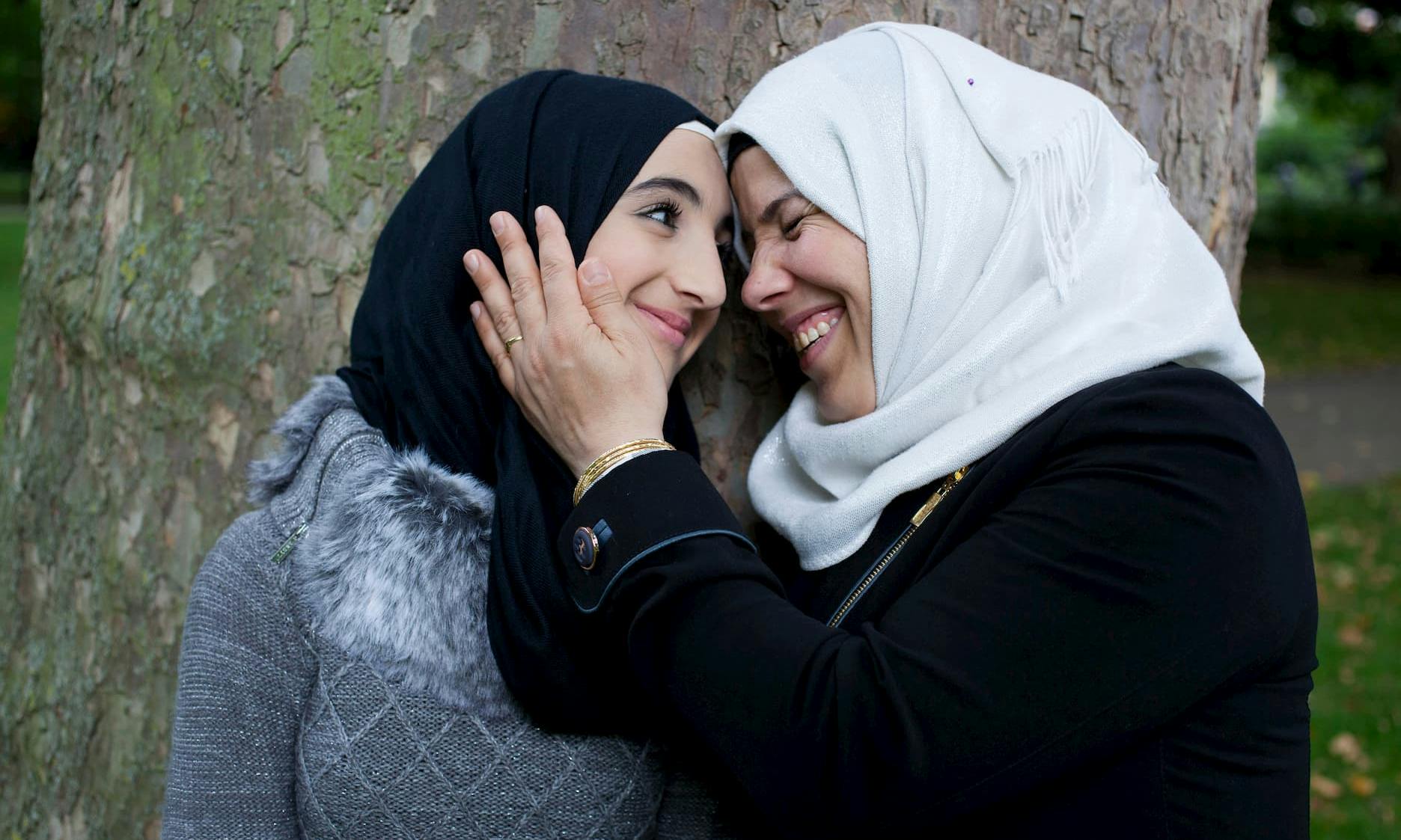 A mother holding the face of her daughter and smiling at eachother