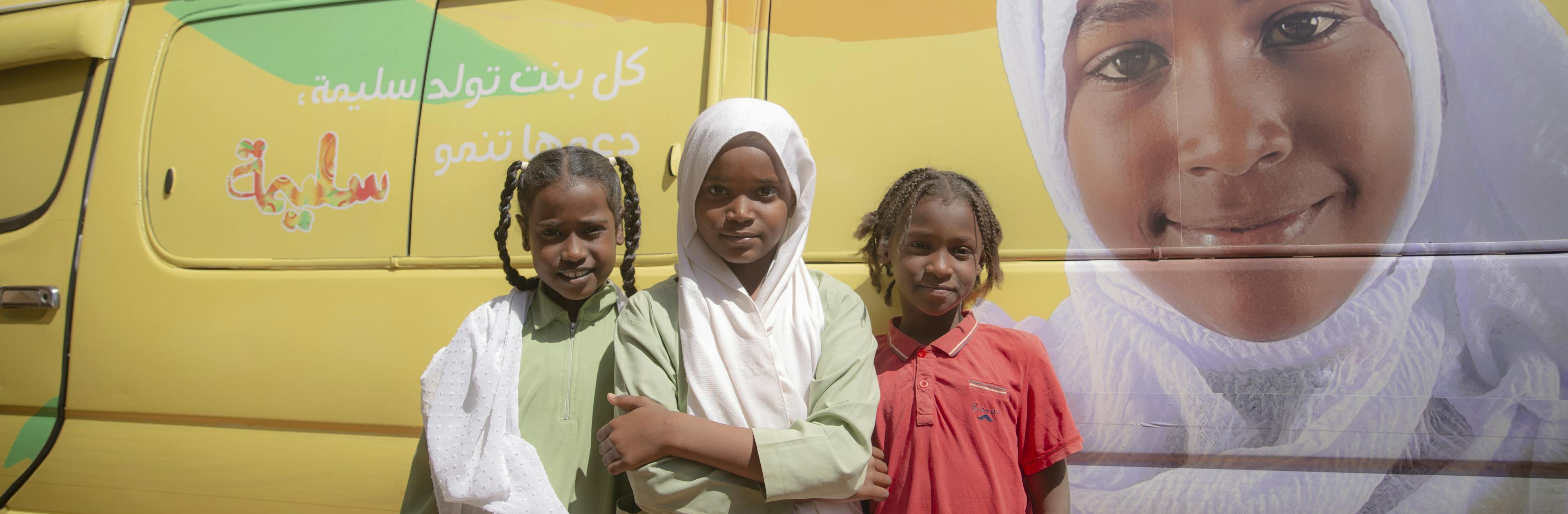 Pupils from Al-fayha Basic School for girls, Khartoum state pose infront of the Saleema caravan during the commemoration event of the International Day of Zero Tolerance for Female Genital Mutilation.