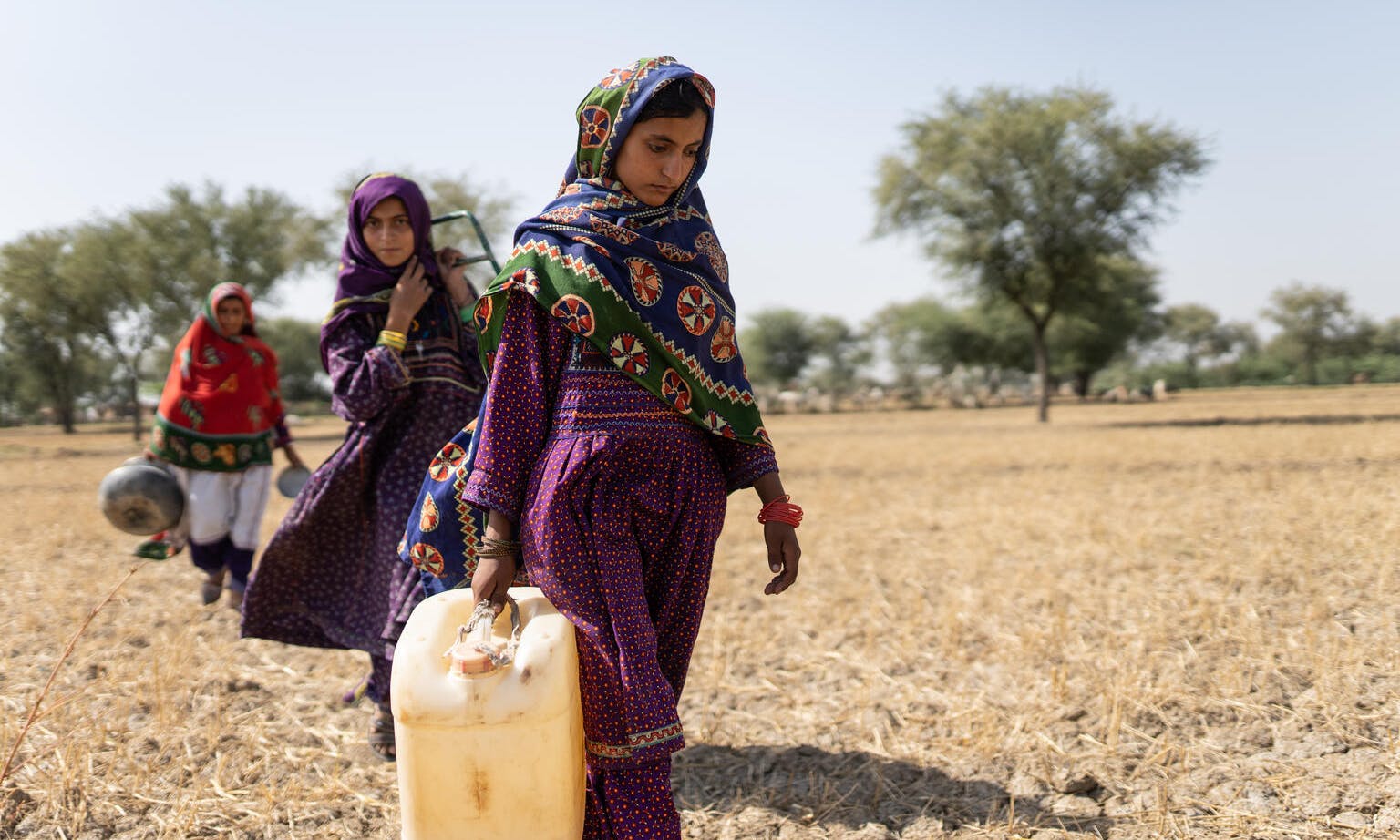 Saima, 10, (right) goes to fetch water with her mother and sister (behind) near a contaminated pond in Allah Abad, Jampur, South Punjab, Pakistan.