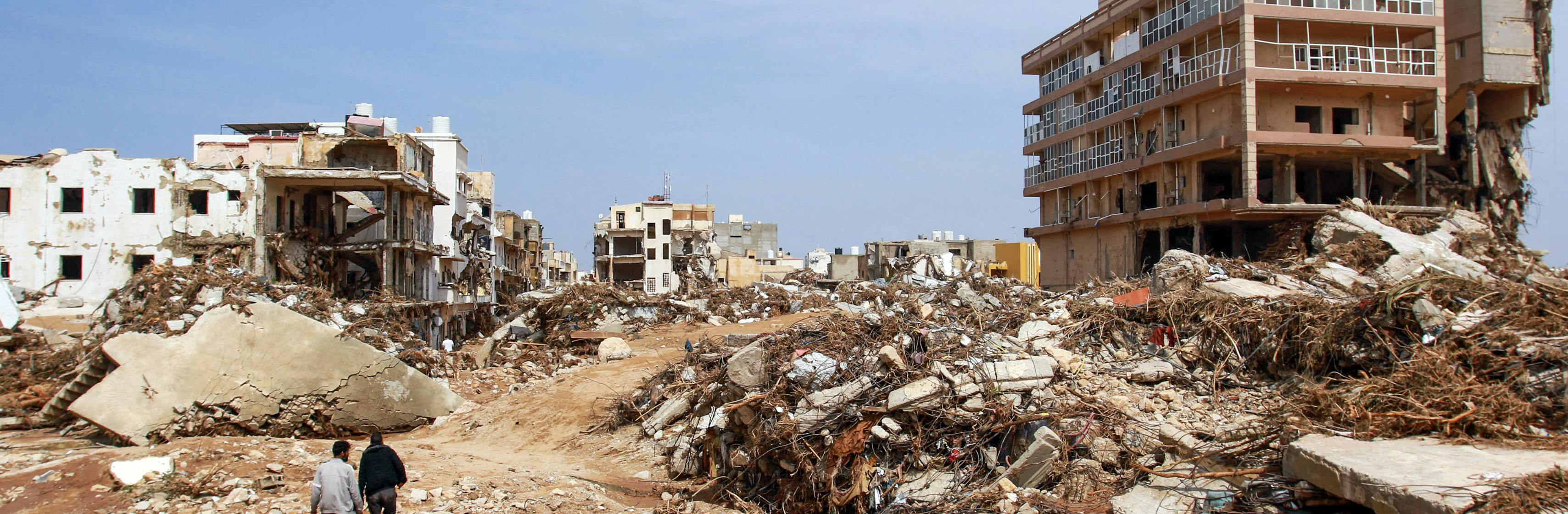 Men walk past debris of buildings caused by flash floods in Derna, eastern Libya. The floods on September 11, 2023 have killed more than 2,300 people.