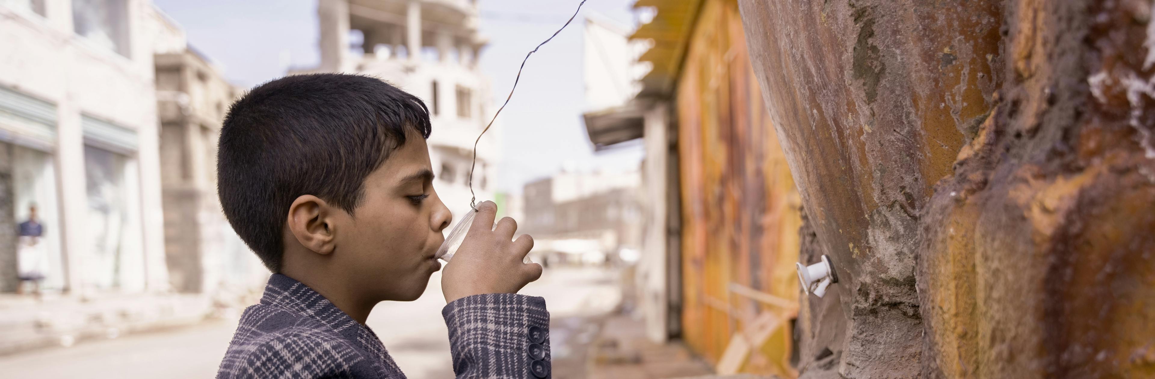 A child is pictured drinking water from a public clay cooler in Dhamar Governorate, Yemen. The availability of clean water is a critical issue in Yemen, where many communities lack access to safe drinking water.