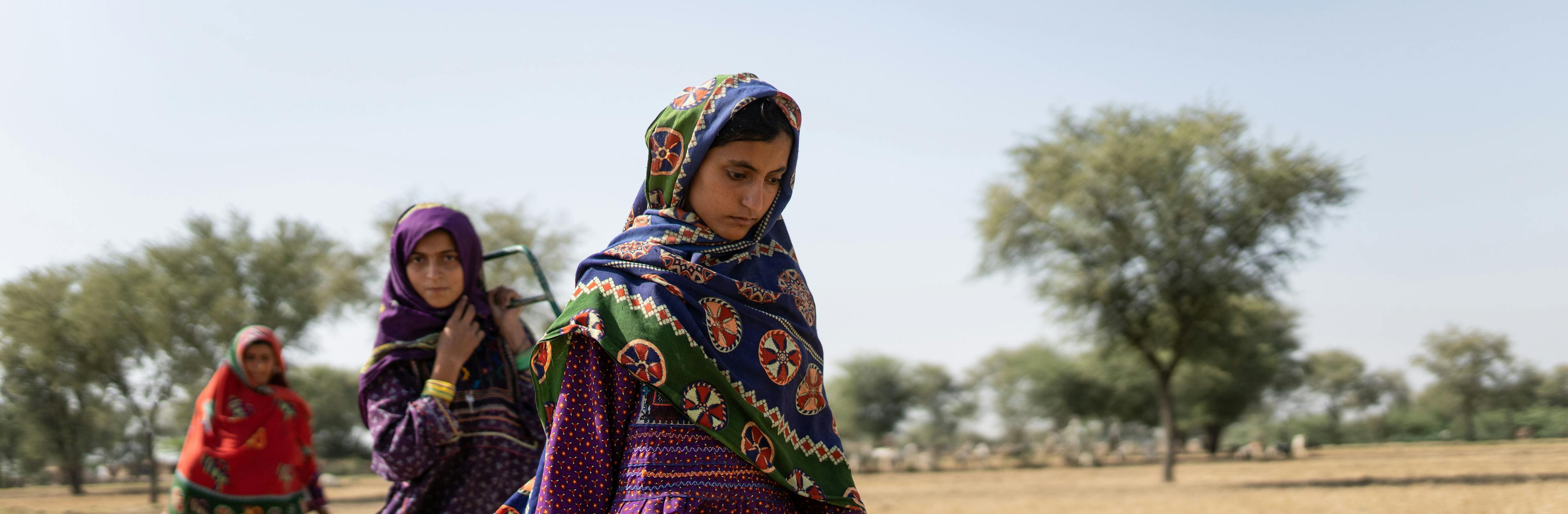 Saima, 10, (right) goes to fetch water with her mother and sister (behind) near a contaminated pond in Allah Abad, Jampur, South Punjab, Pakistan.