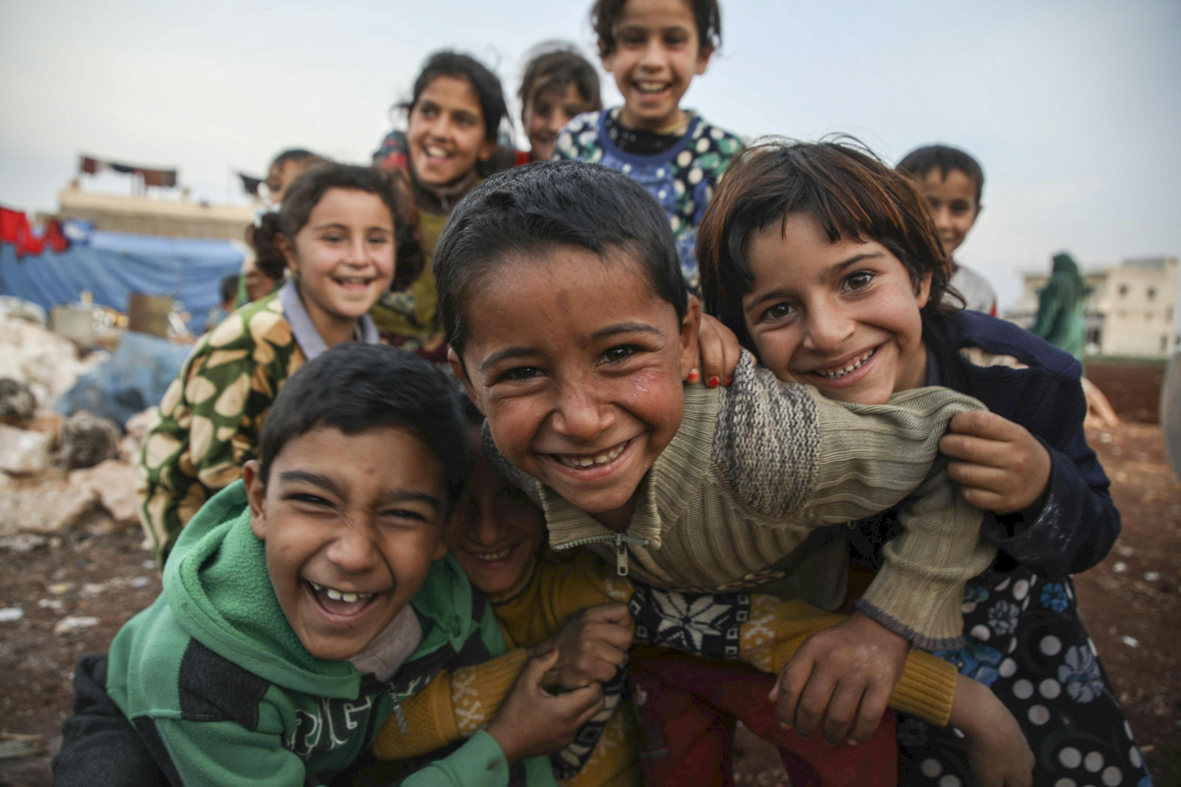A group of children laugh and smile at the camera in Syria