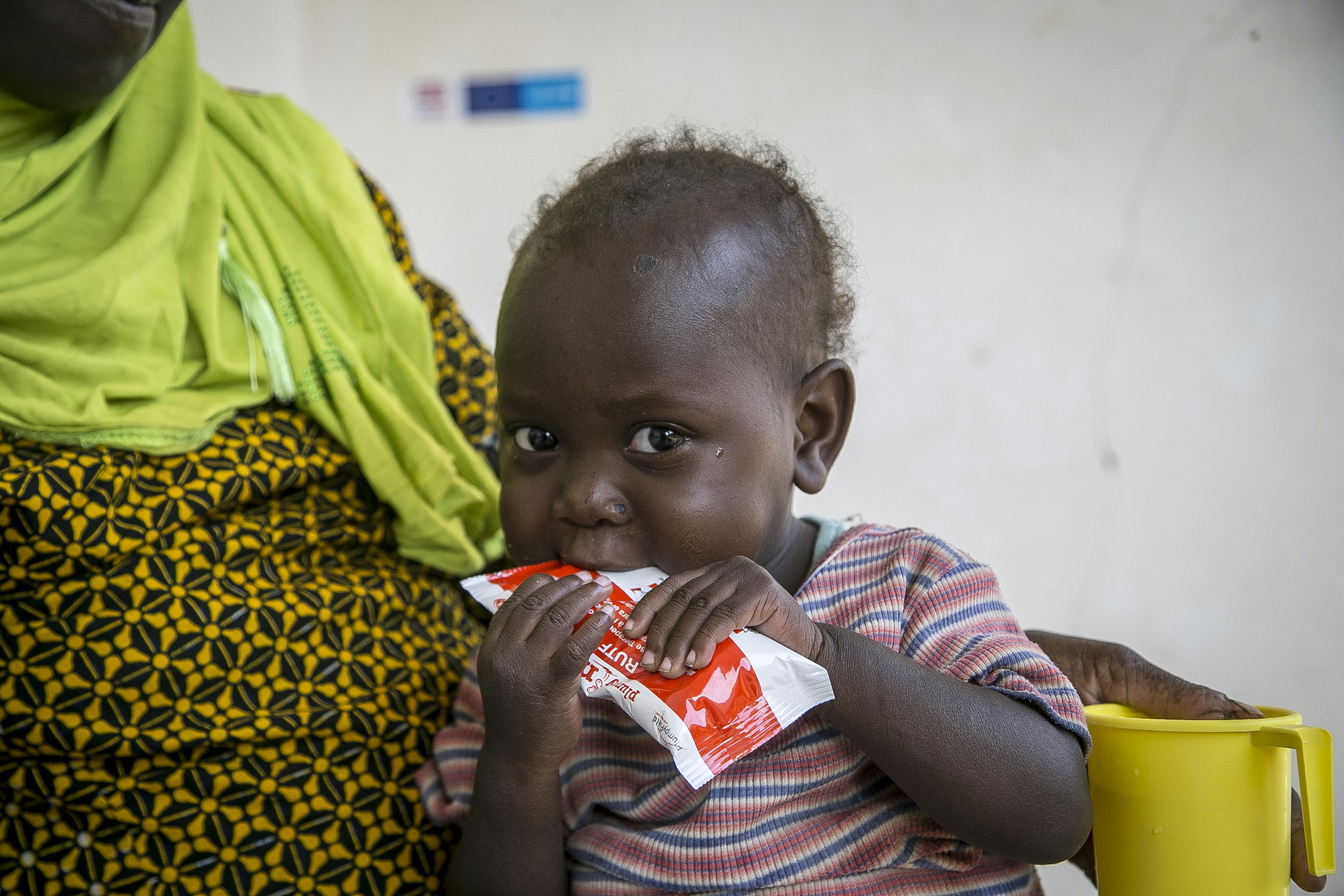 Oumou Bah, 2, eating ready-to-use therapeutic food