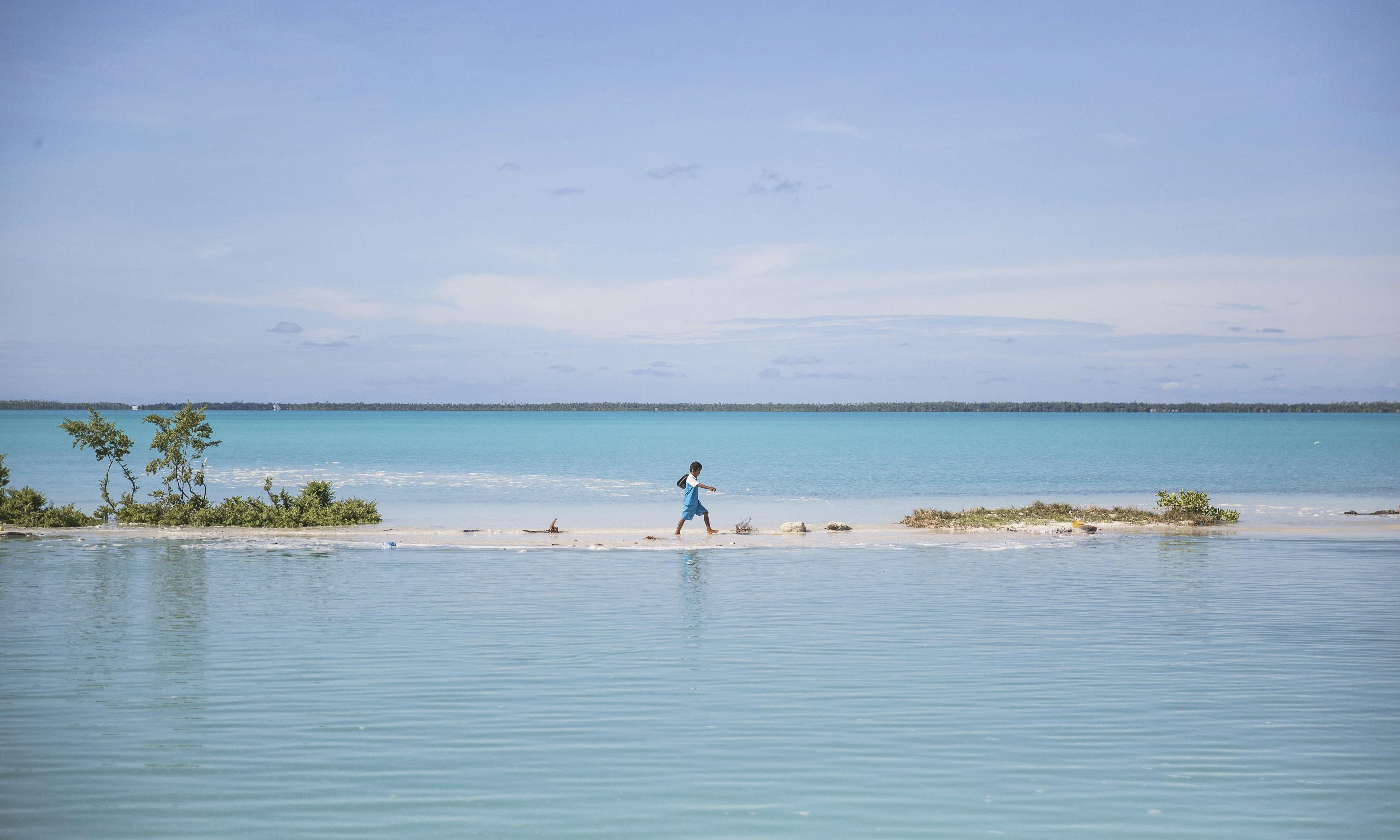 A boy walks from school to his house in Aberao village in South Tarawa, Kiribati. Kiribati is one of the countries most affected by sea level rise. During high tide many villages become inundated making large parts of the villages uninhabitable.