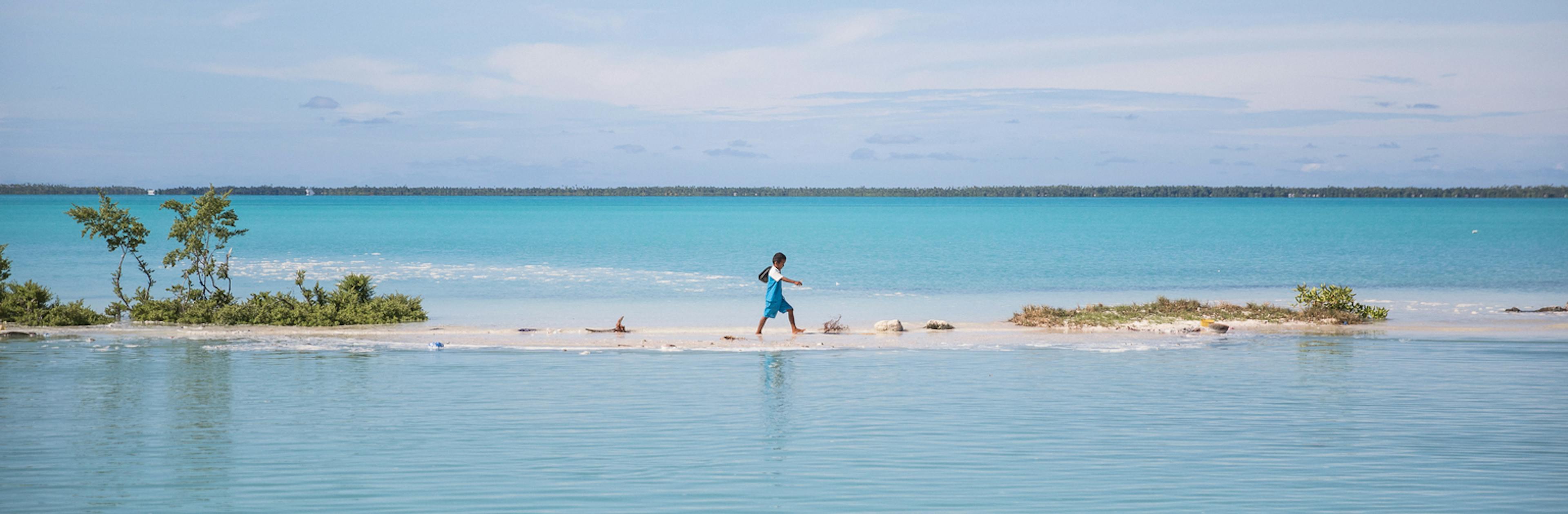 A boy walks from school to his house in Aberao village in South Tarawa, Kiribati. Kiribati is one of the countries most affected by sea level rise. During high tide many villages become inundated making large parts of the villages uninhabitable.