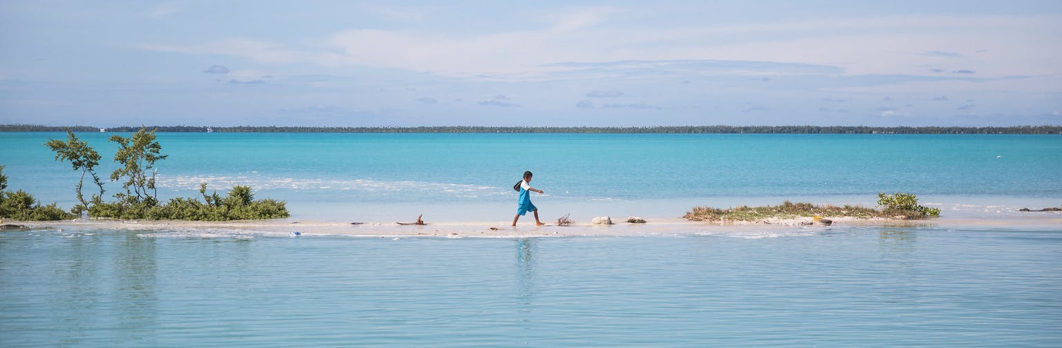 A boy walks from school to his house in Aberao village in South Tarawa, Kiribati. Kiribati is one of the countries most affected by sea level rise. During high tide many villages become inundated making large parts of the villages uninhabitable.