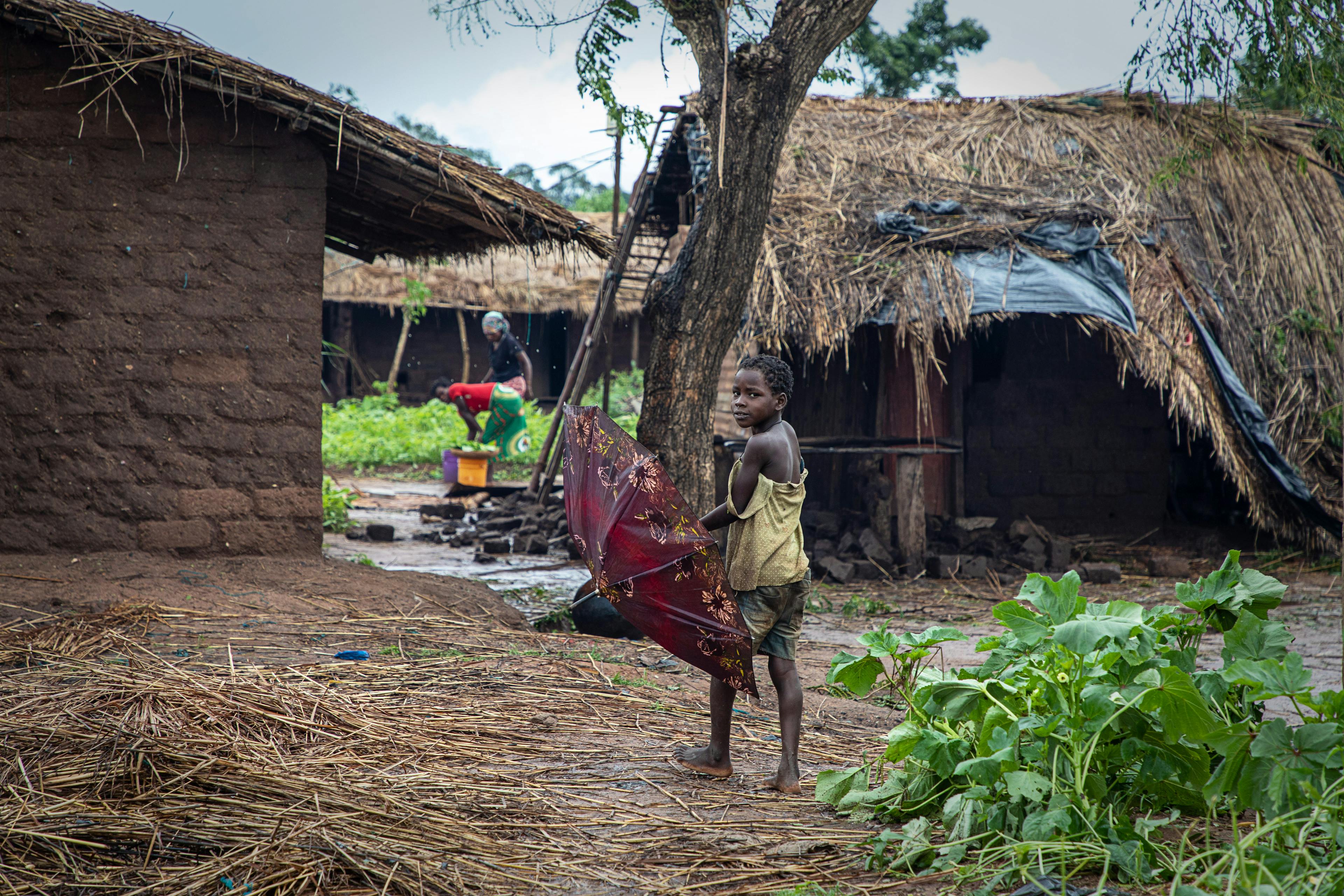 Young child in village holding umbrella