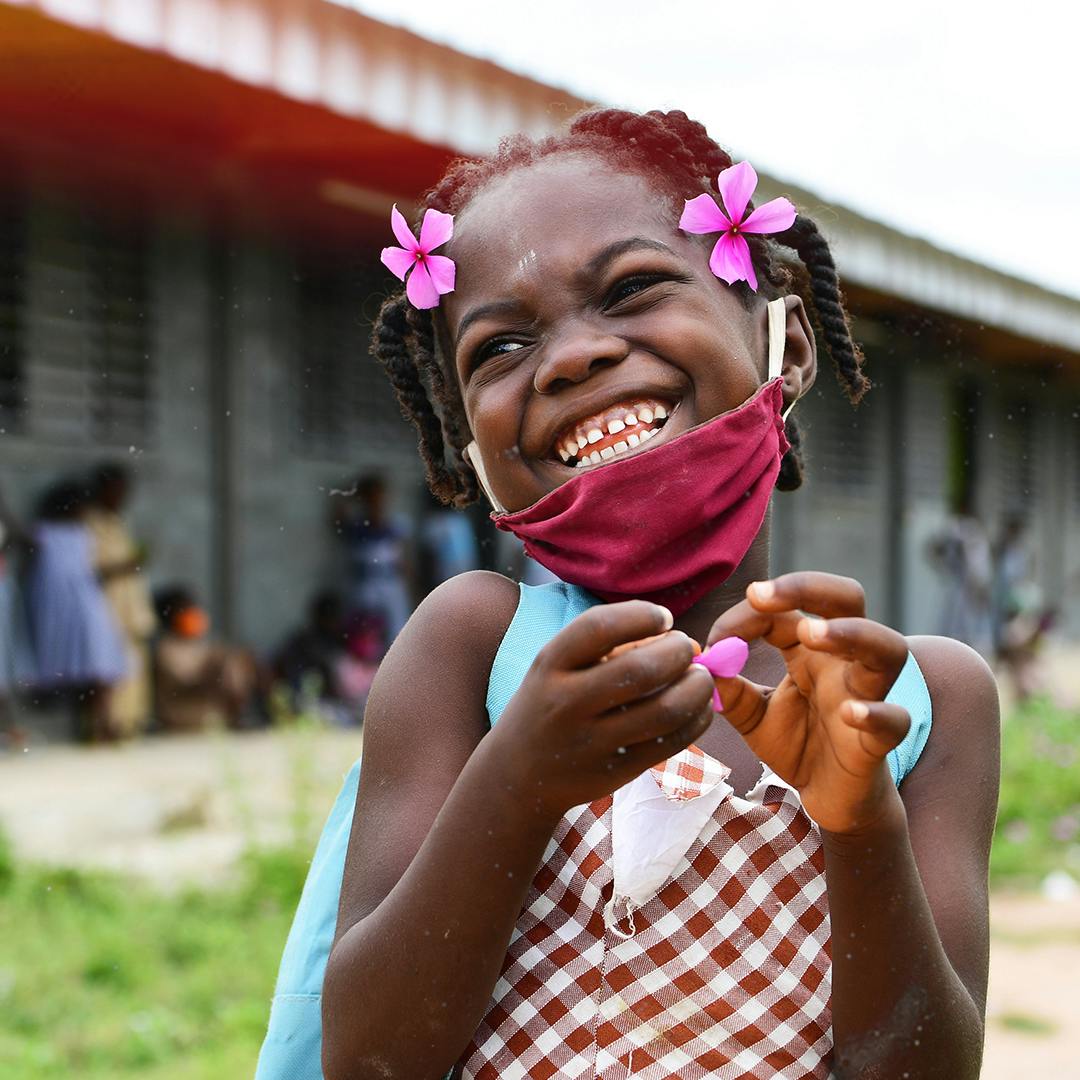 young girl with a big smile wearing a face mask