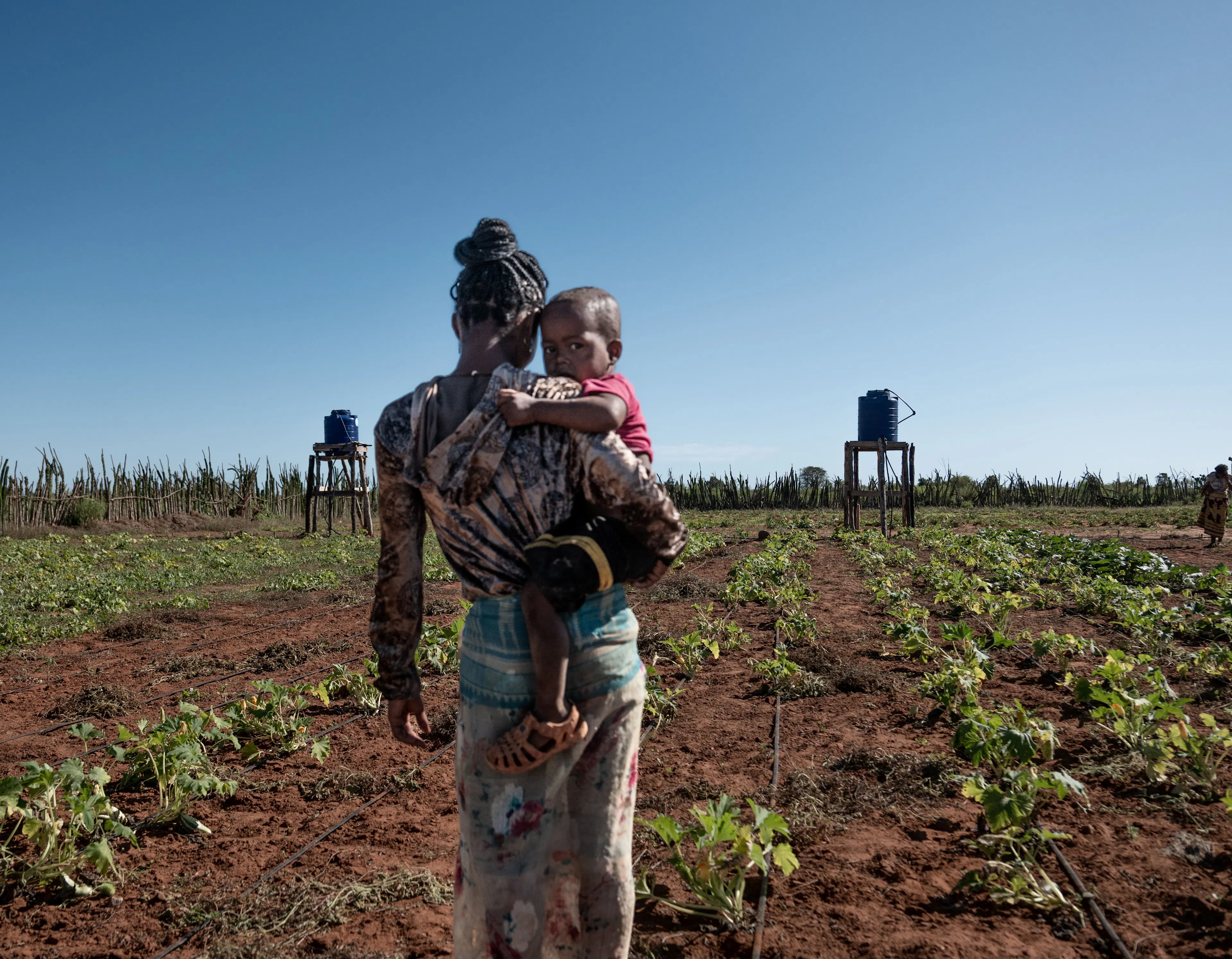 A mum holding her child walking through the the vegetable garden that is part of the "Multiple Use of Water" System in Ehavo Public Primary School in Madagascar. 