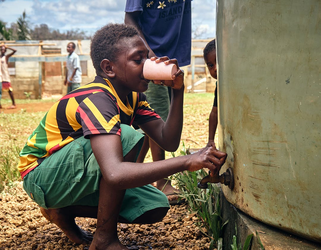 A boy drinking water from rainwater tank in Fiji.