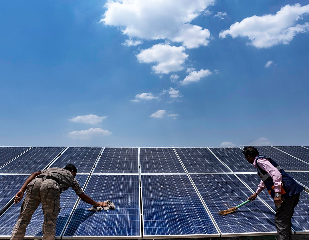 On 08 June 2023, workers clean the solar panels for the solar cold chain point installed on the rooftop of the Health and Wellness Centre in Pithoria, Jharkhand state, India.