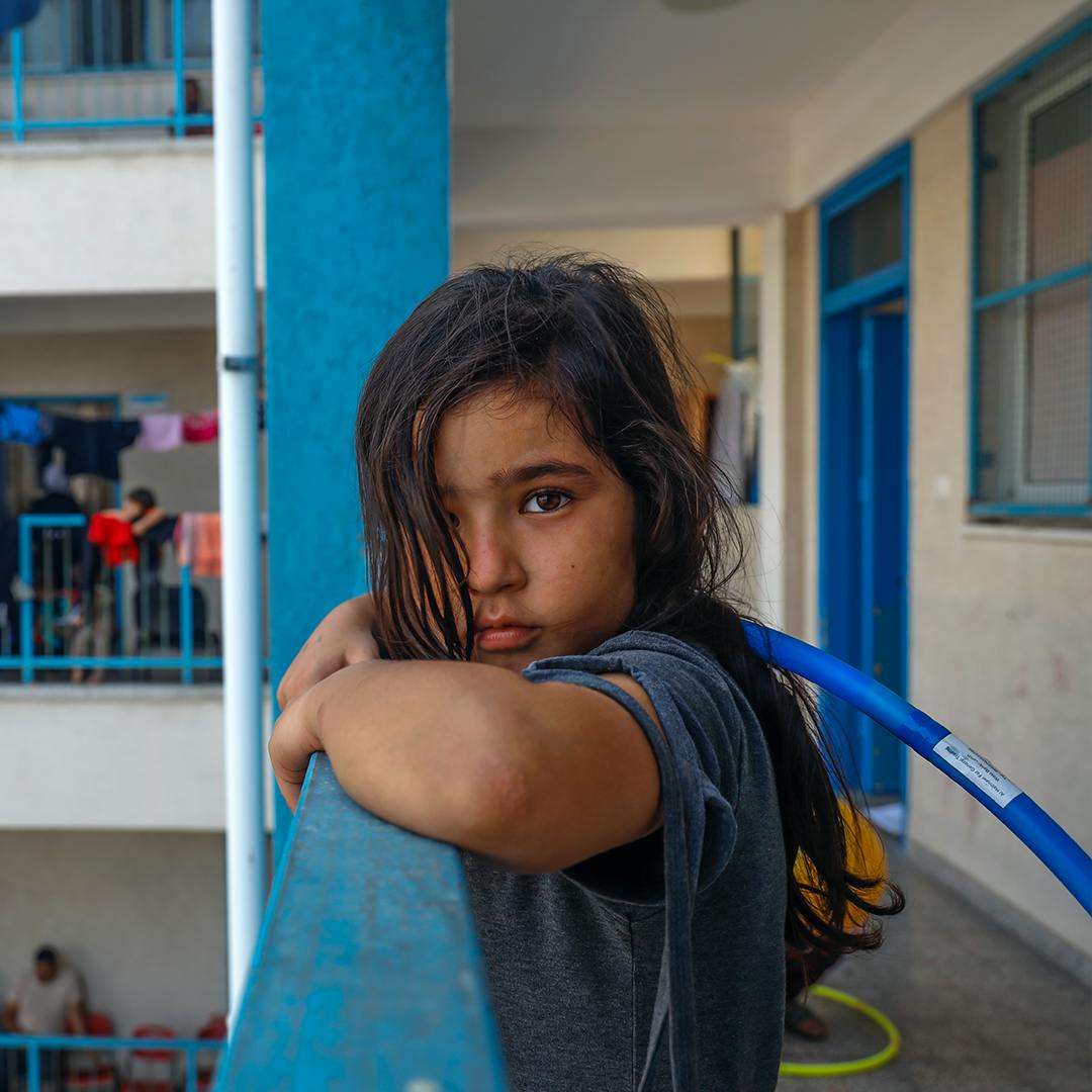 Jannat, an 8-year-old girl, watching other children play in the UNRWA school playground. "I want to play with them but I am afraid to leave the room. I don’t know how they can play without being scared, I just want to go back home", she said.