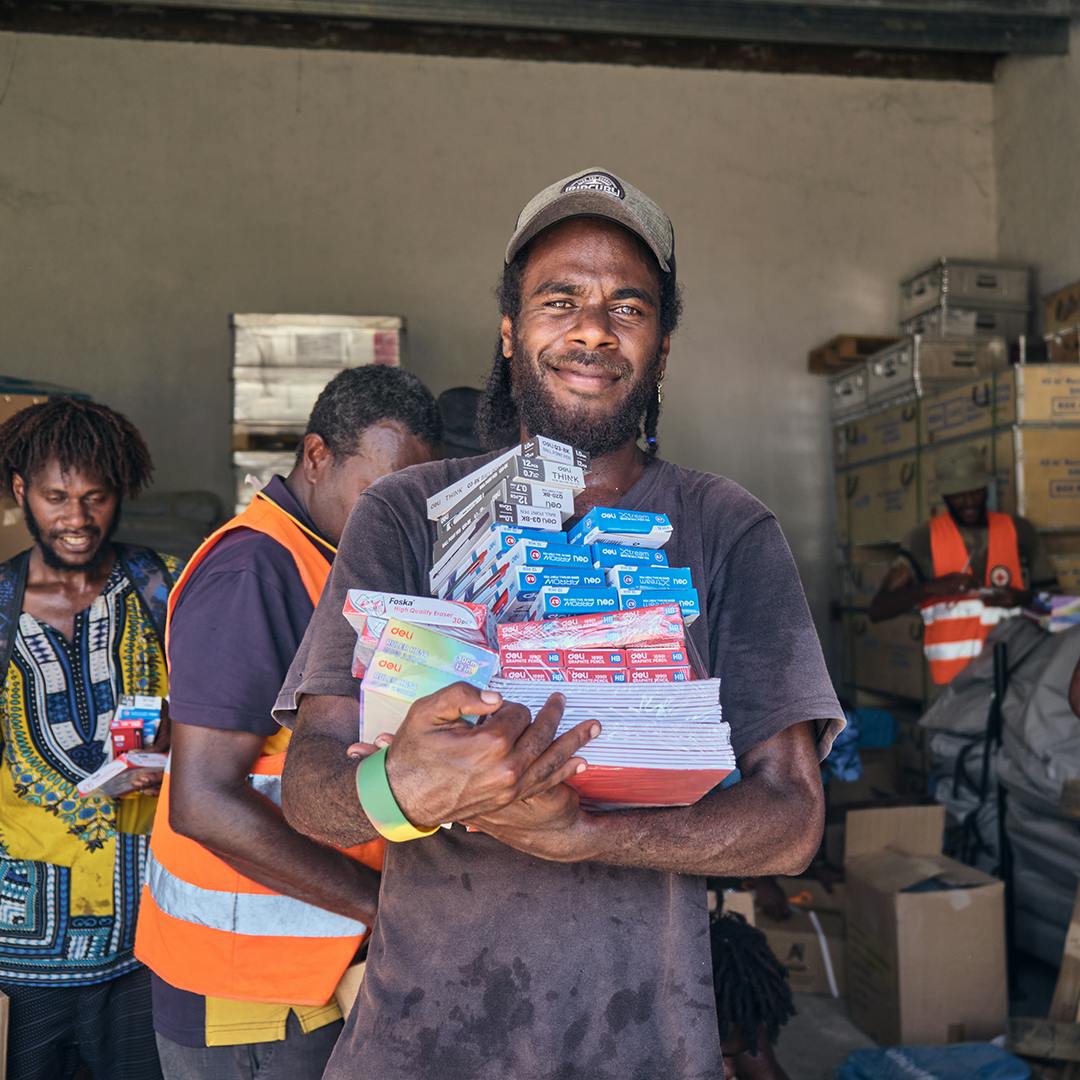 Red Cross volunteers are tasked with preparing UNICEF school bags for distribution to schools. A volunteer carries some stationary.