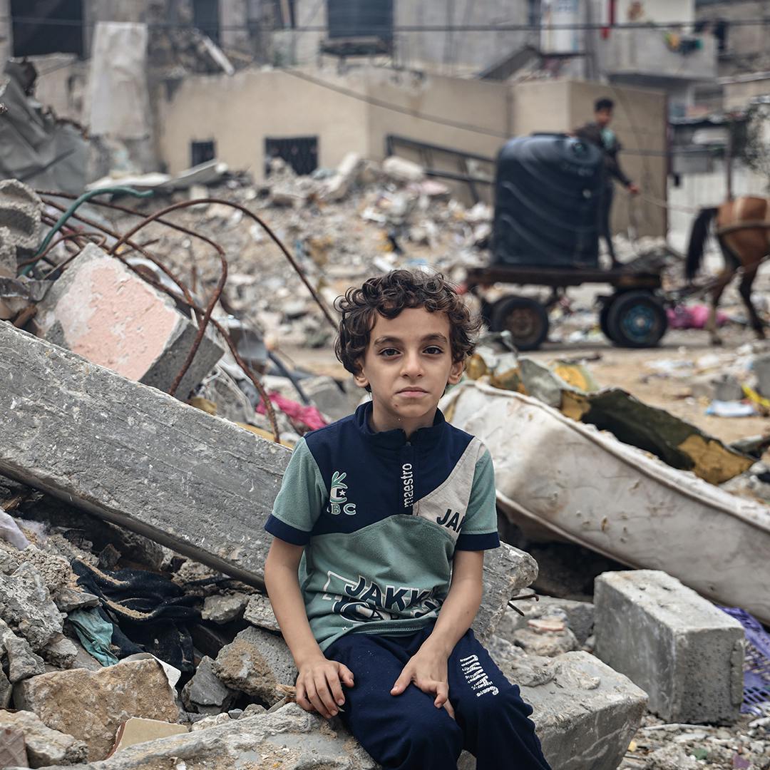 Mohammed Alattar, 8-year-old from Rafah City, sits on the rubble of his family's house, which was bombed in an Israeli airstrike.