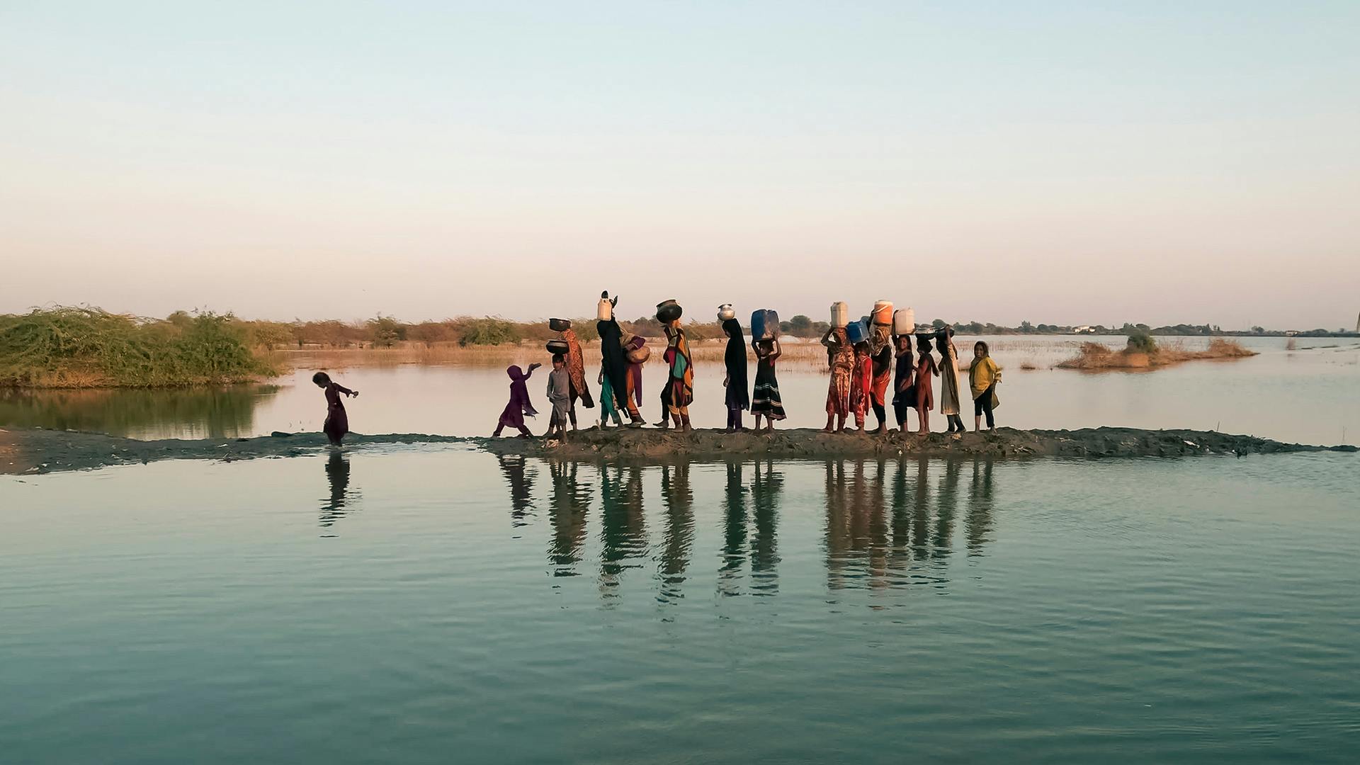 Women and girls walking with their buckets to fetch water in the inundated region of Geokaloi village in the Southern Pakistani province of Sindh.