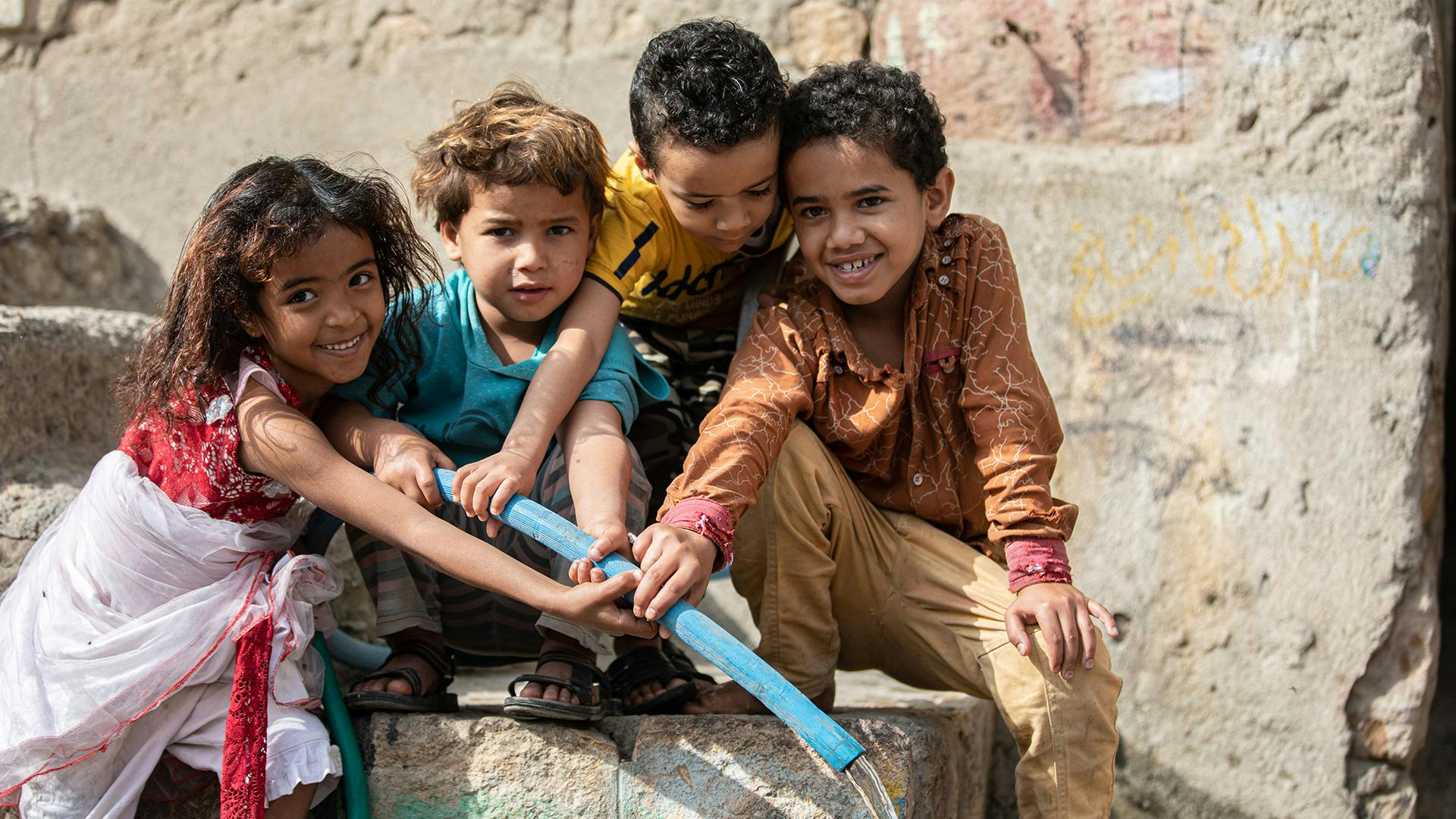 Children while filling a pail with water in Al Nusayria Neighborhood - Al Mudhaffar District - Taizz Governorate, Yemen, and they are extremely happy with the water arrival.