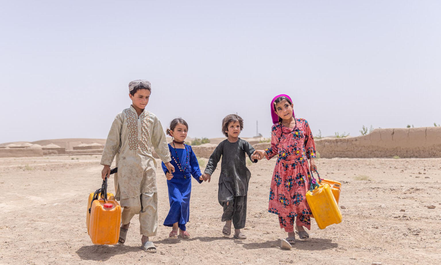 Children walk with their jerry cans to collect water from a UNICEF supported tap, located in the heart of their village in Badghis Province, Afghanistan.  