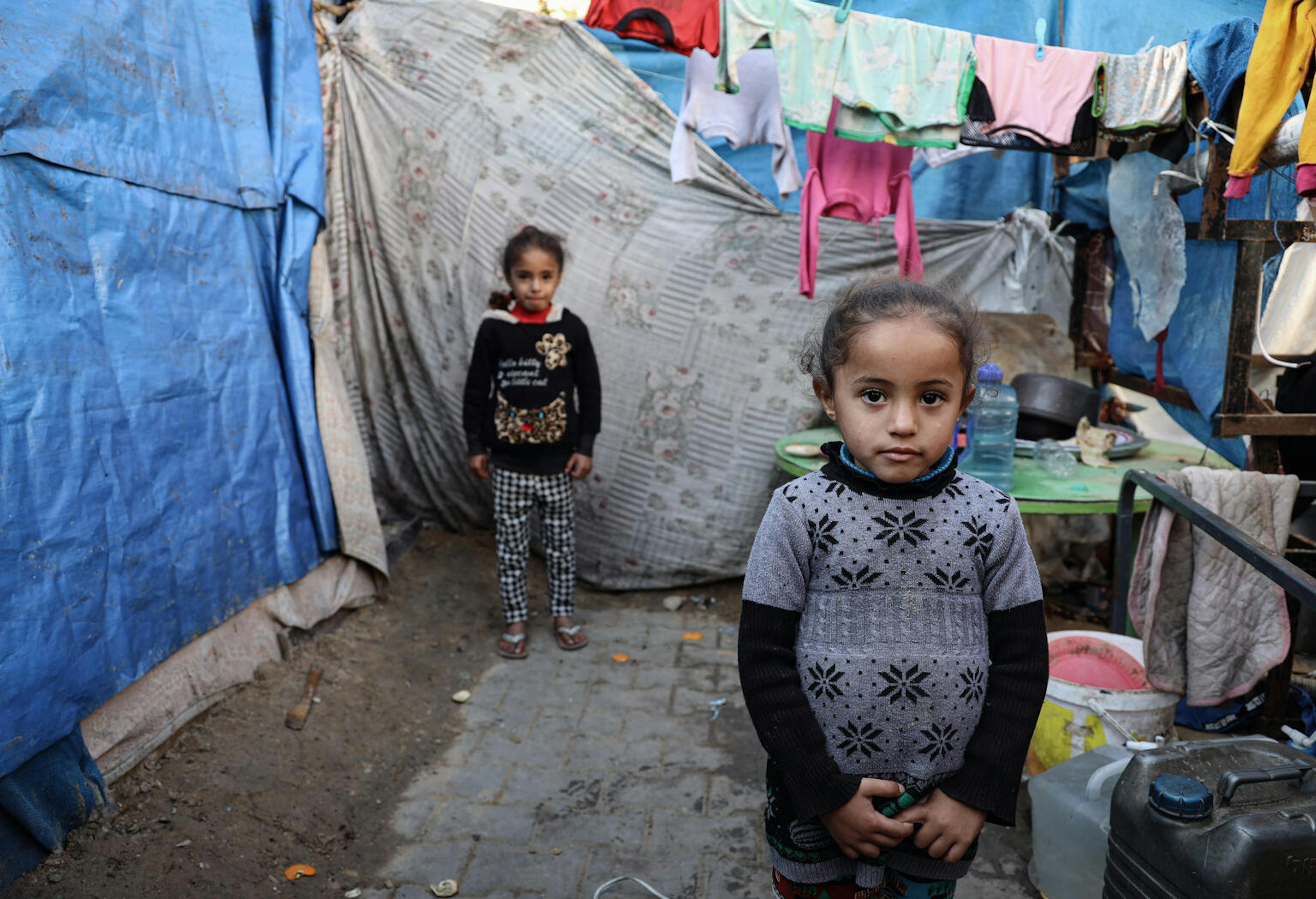 Sisters, 4-year-old Maria, front, and 9-year-old Dalia, pose for a photograph at their family's makeshift tent in a shelter for internally displaced persons in Rafah, southern Gaza.
