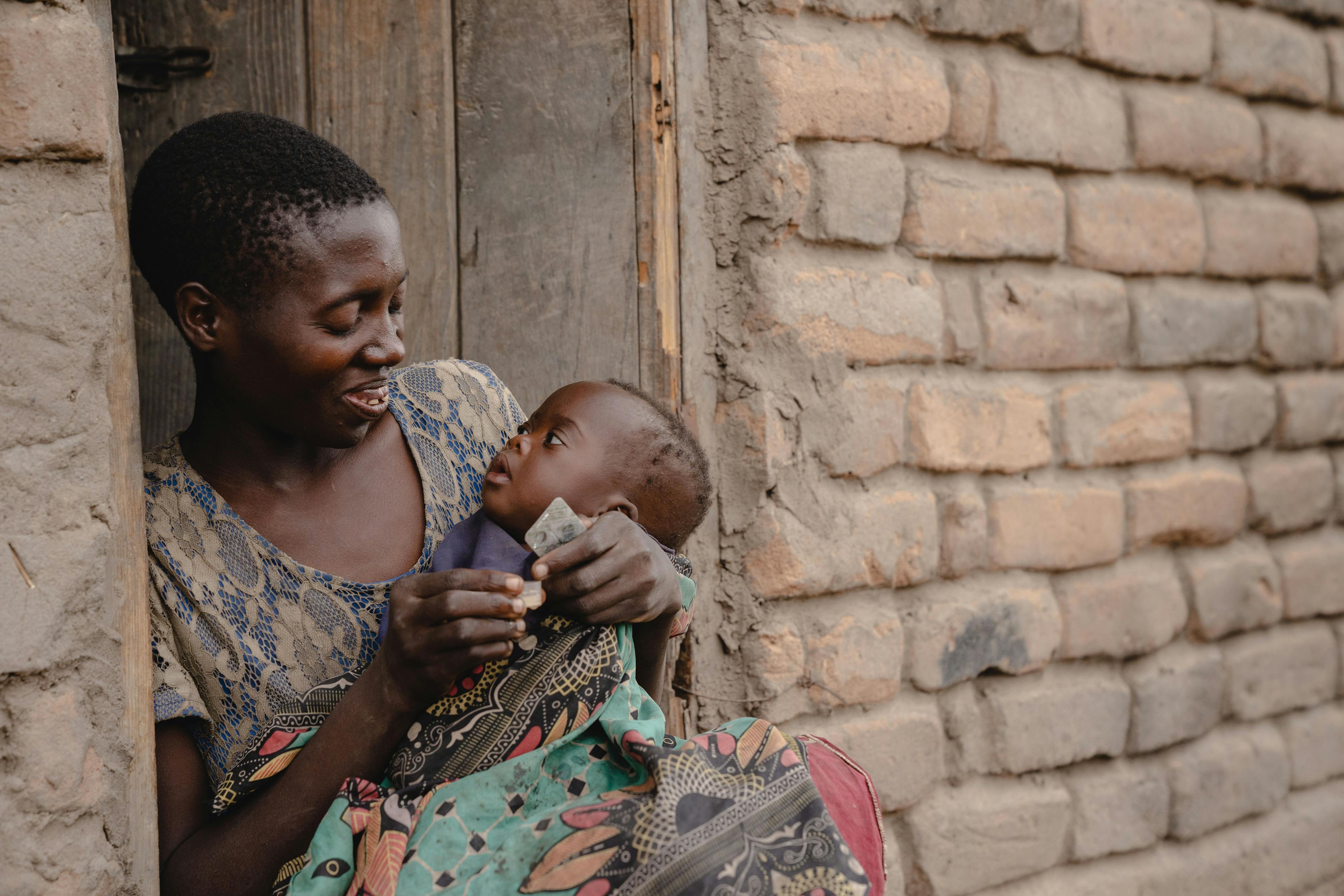 Jeany (Mwale 24 years) giving (malaria) medicines to her 4 months old daughter (Roda) (at her home in Mpuphila Village.