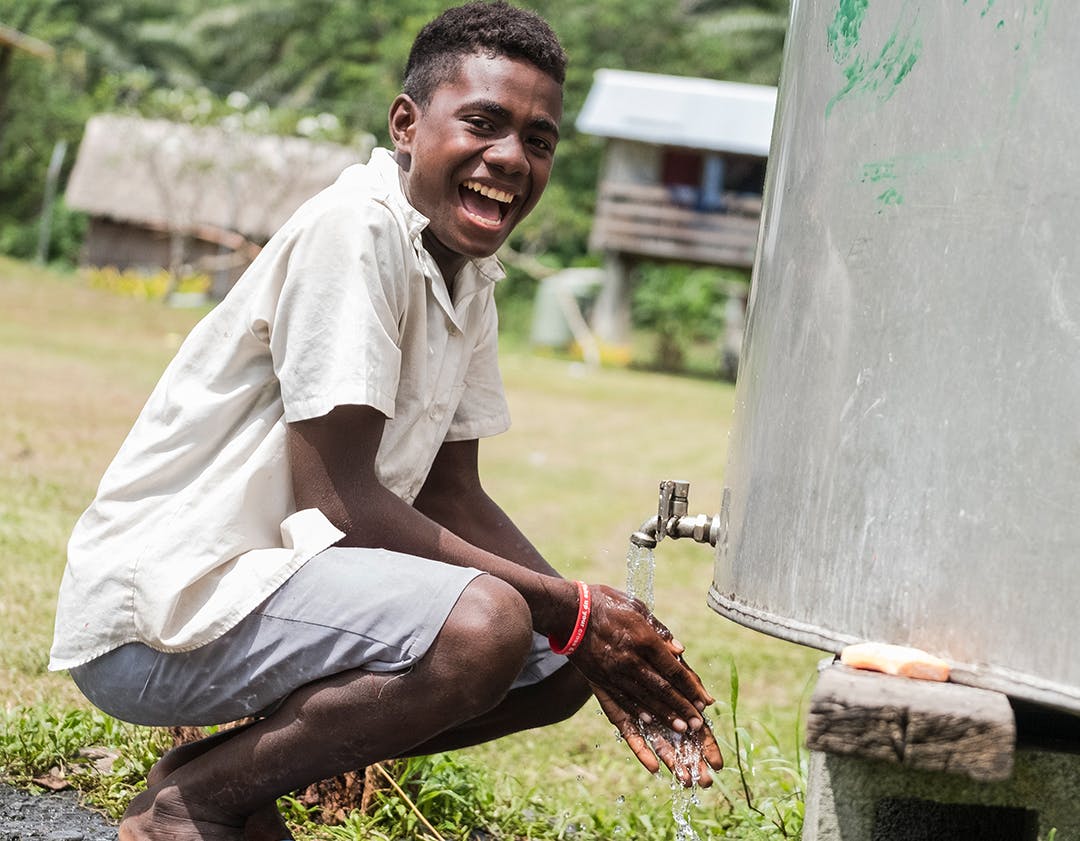 Julio, 14, washing her hands from a water tank, funded by UNICEF. Nguvia Primary School, Guadalcanal Province, Solomon Islands.