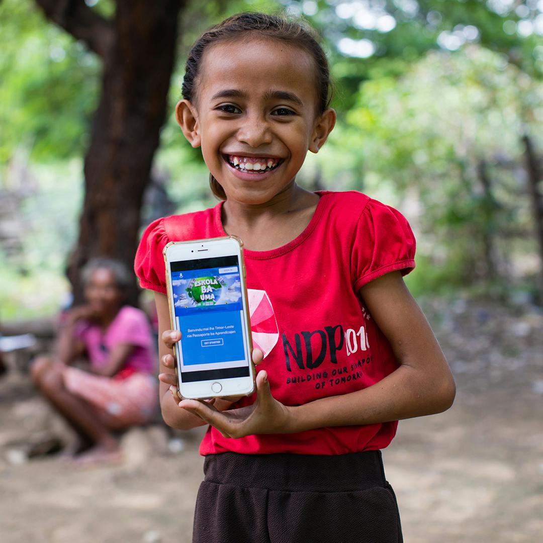 A child holding a phone with the app 'Learning Passport' for remote learning classes