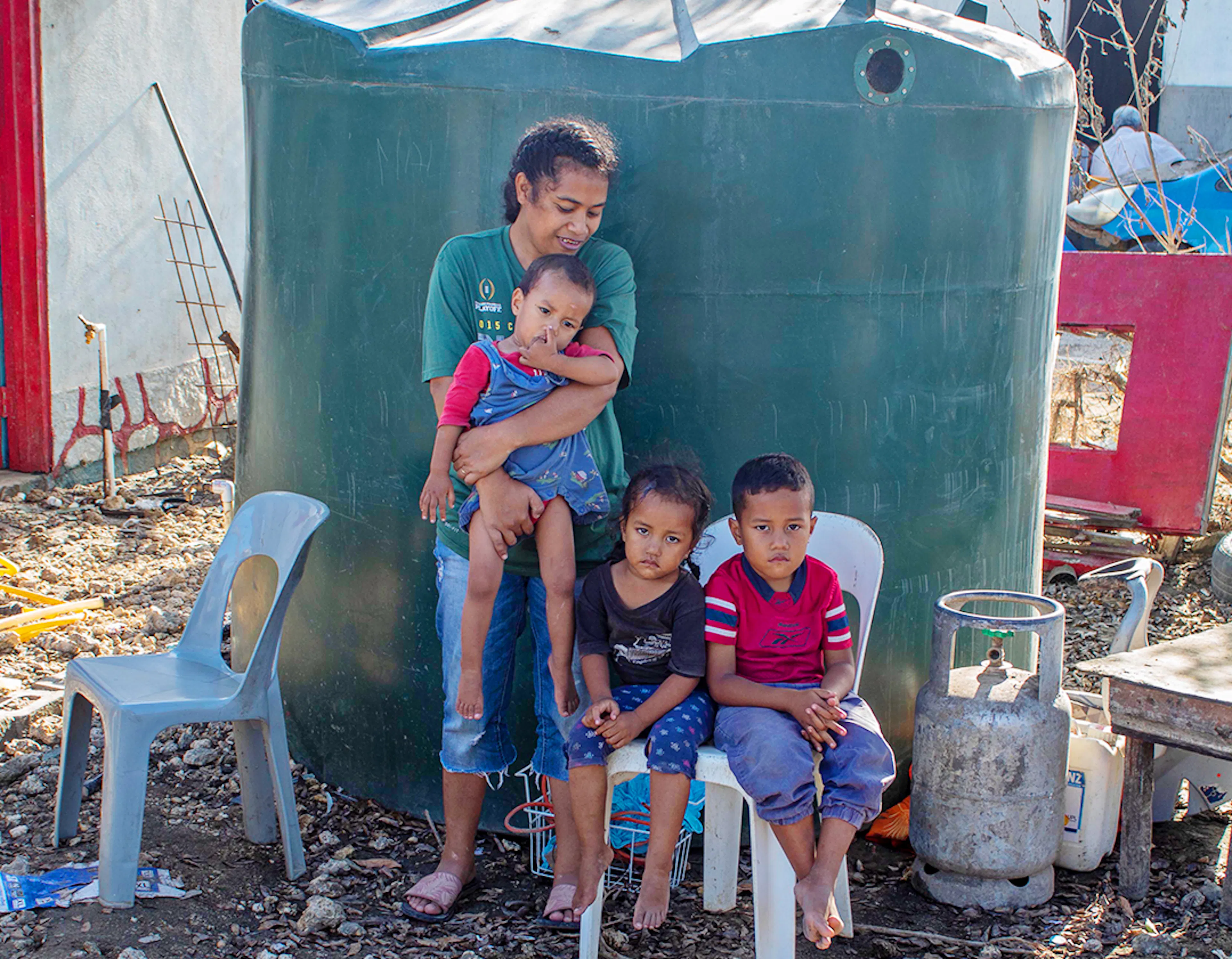 On 22 January 2022, Wesley Makahokovalu Masoe (5yr), Seluvaia Masoe (3yr), and Elenoa Masoe (1yr), with their mother, Moana, outside their home in Patangata Village on Tongatapu, Tonga’s main island, caused by the Hunga Tonga-Hunga Ha’apai underwater volcano eruption and tsunami. 