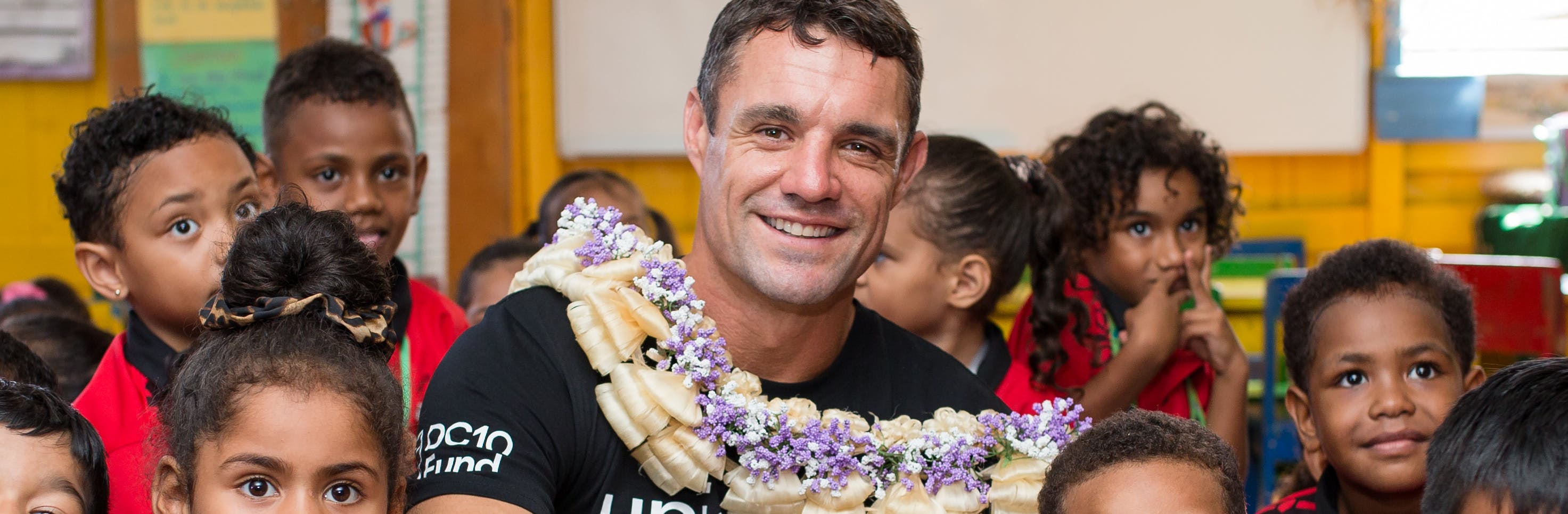 Dan Carter smiles with a group of school students on his trip with DC10 UNICEF to the Pacific