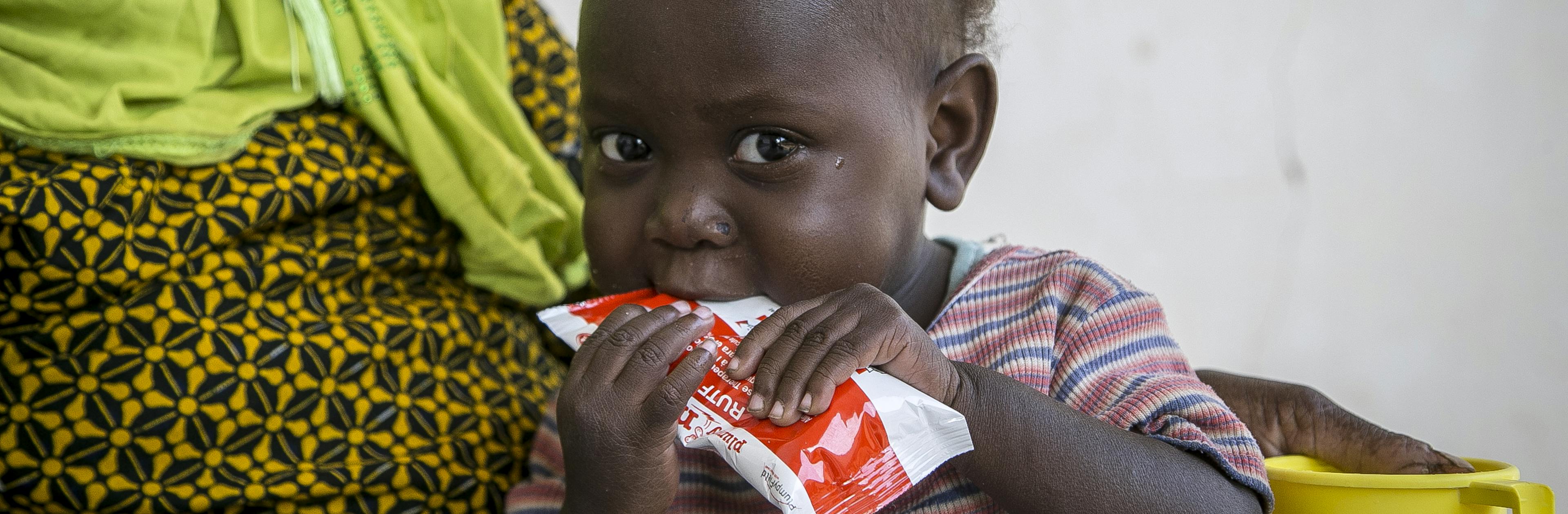Oumou Bah, 2, eating ready-to-use therapeutic food