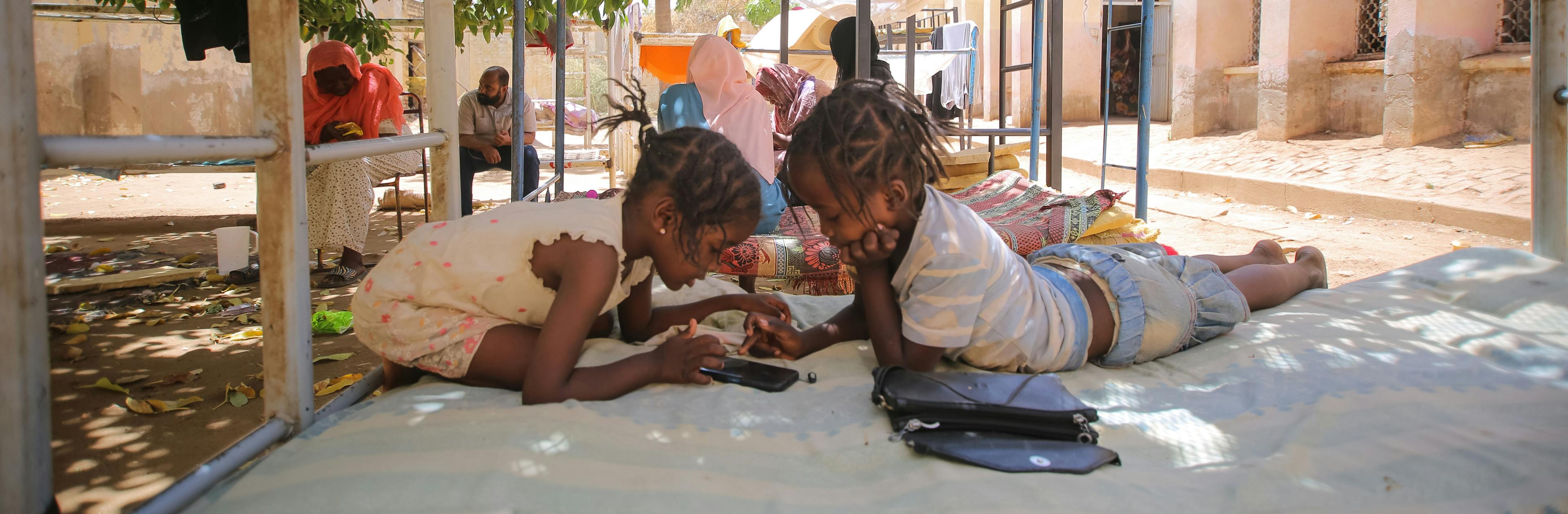 On 12 May, displaced children play games on a mobile phone at a temporary shelter.