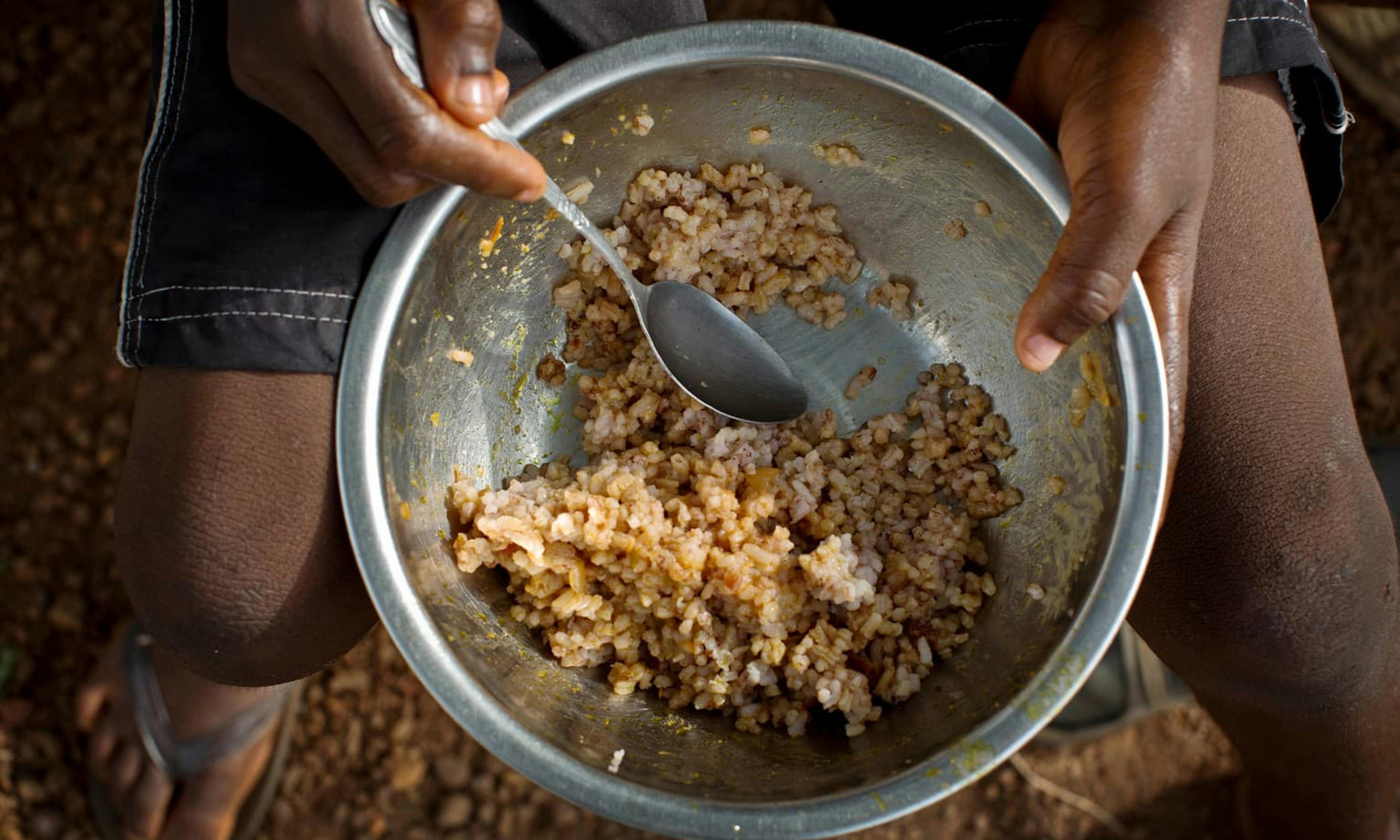 A young boy eats a bowl of rice as his only meal that day at a home near Kenema, Sierra Leone