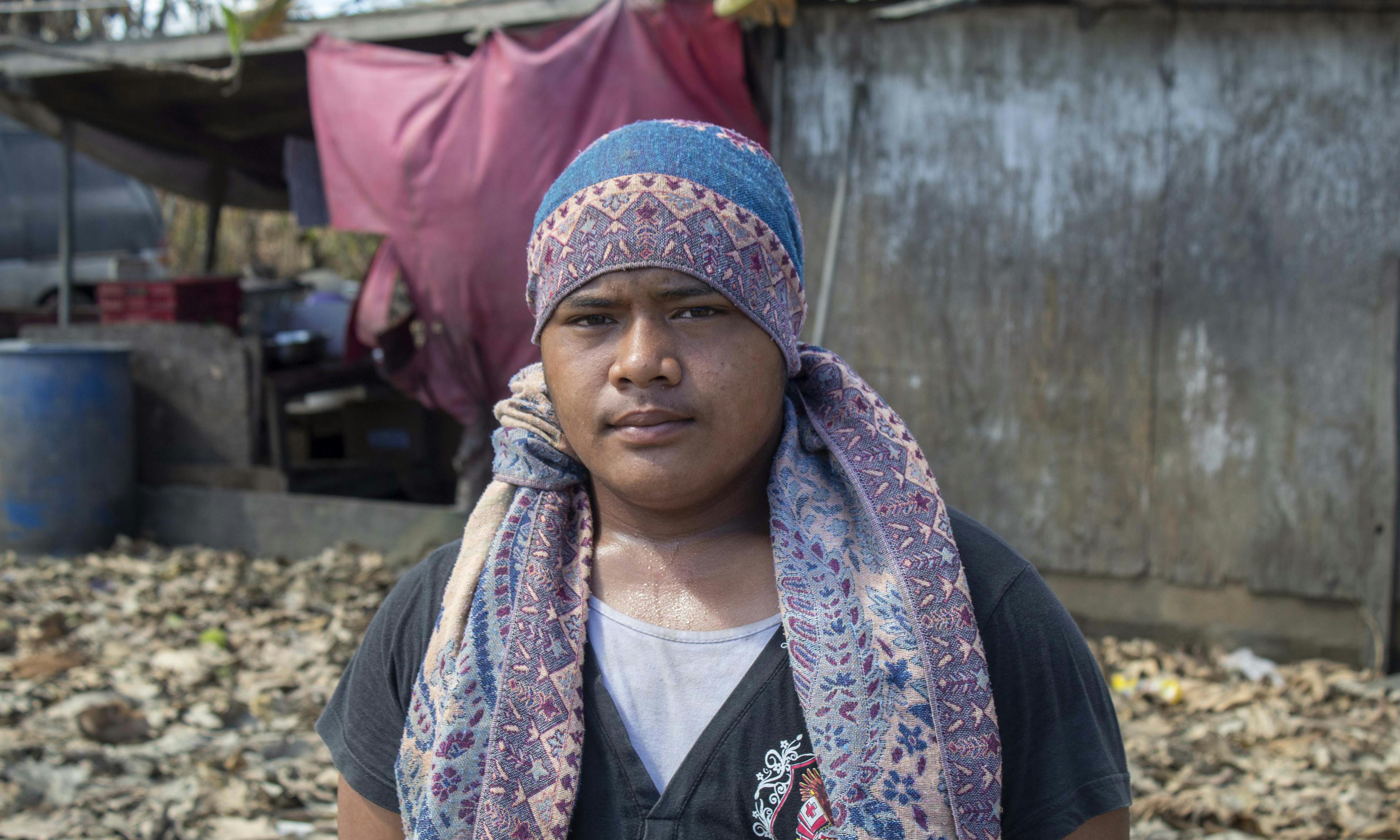On 22 January 2022, Semisi Fataua, 15 years old, stands in front of his home in Kanokupolu village on Tongatapu, Tonga’s main island, with damage caused by the Hunga Tonga-Hunga Ha’apai underwater volcano eruption and tsunami. 