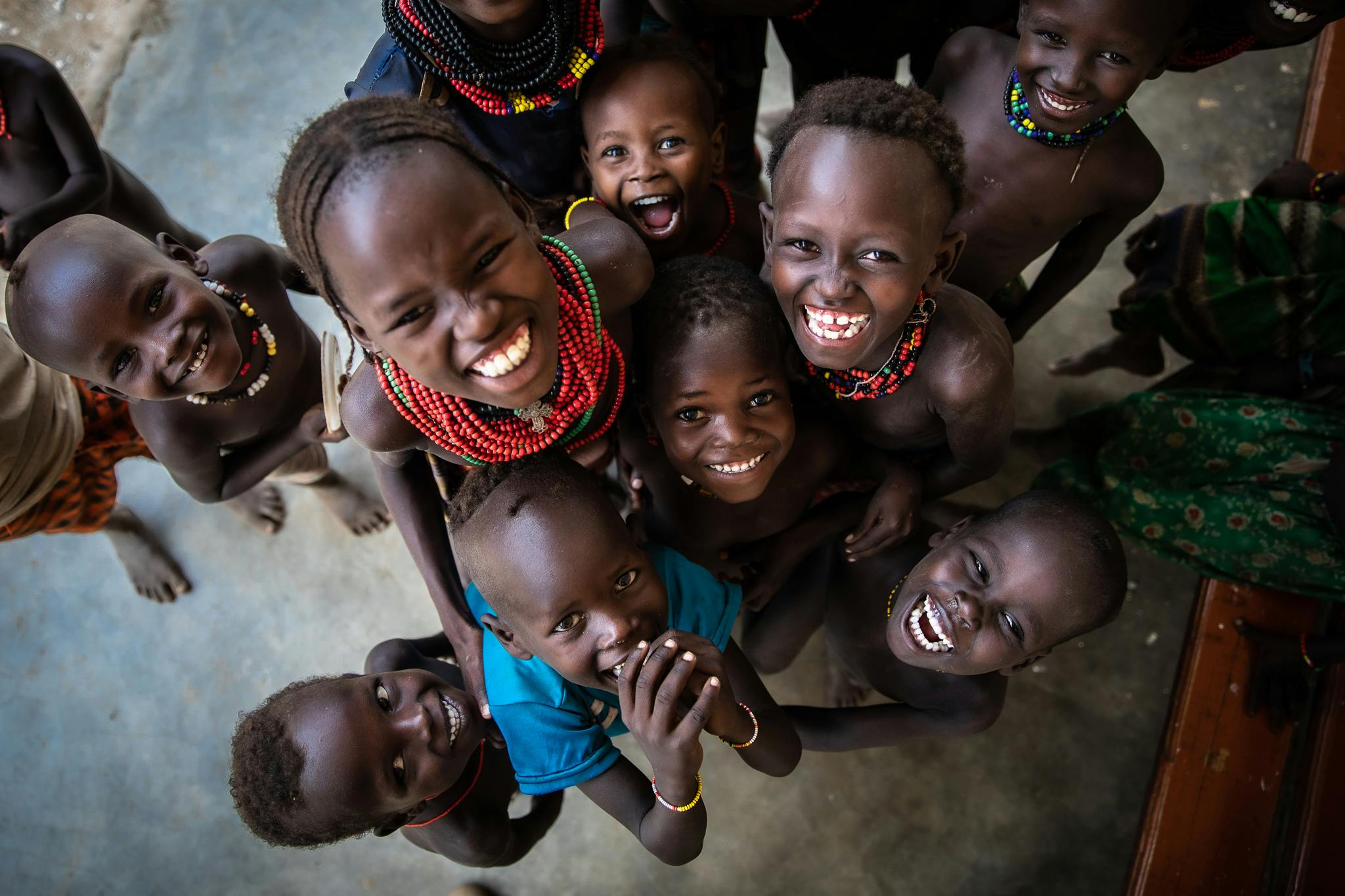Contact Us- A group of young people smile for the camera in the southern Ethiopian township of Omo Rate