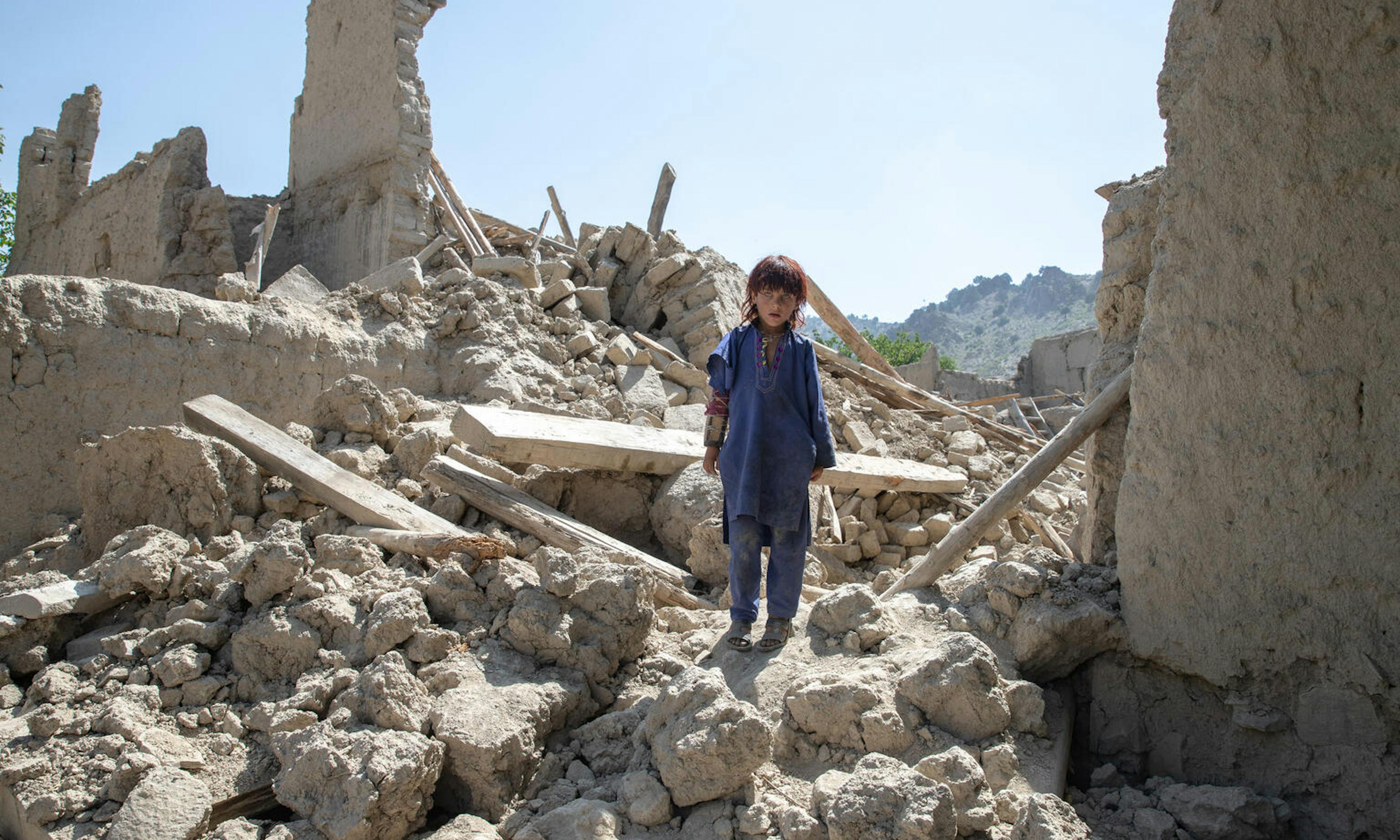 Zaid Allah, 6, stands in the rubble of his home where most of his family died as a result of the devastating earthquake on 22 June.