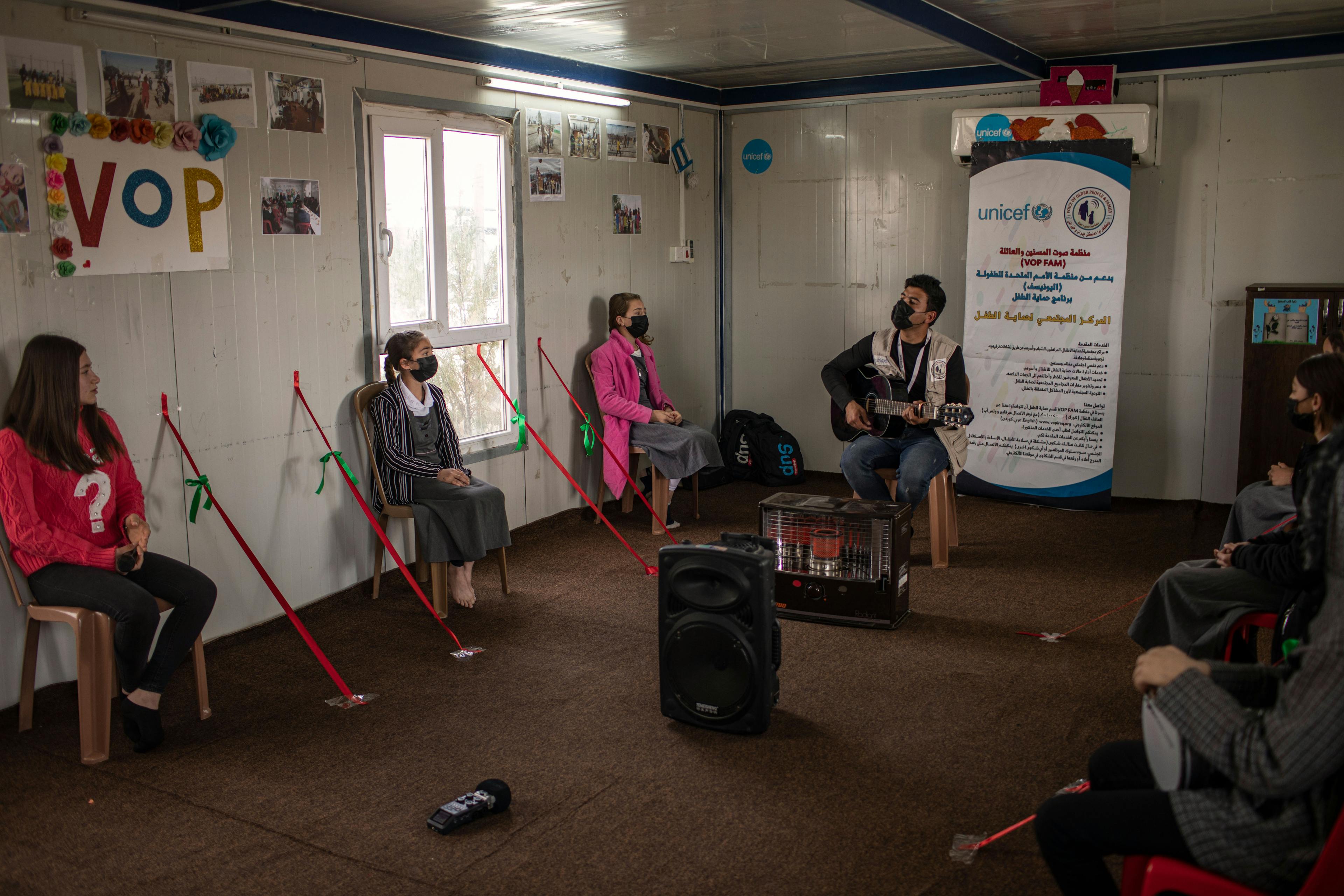 On 8 March 2022 in Iraq, a UNICEF team member leads a music activity for Yazidi children inside a child-friendly space in Shekhan camp for internally displaced persons (IDPs).