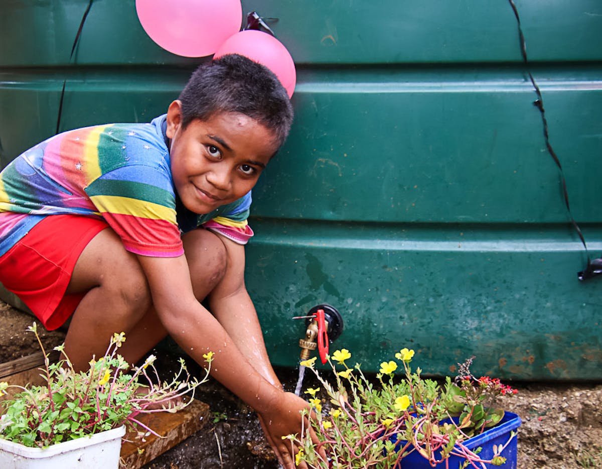 A child in the Pacific watering his plants with clean water