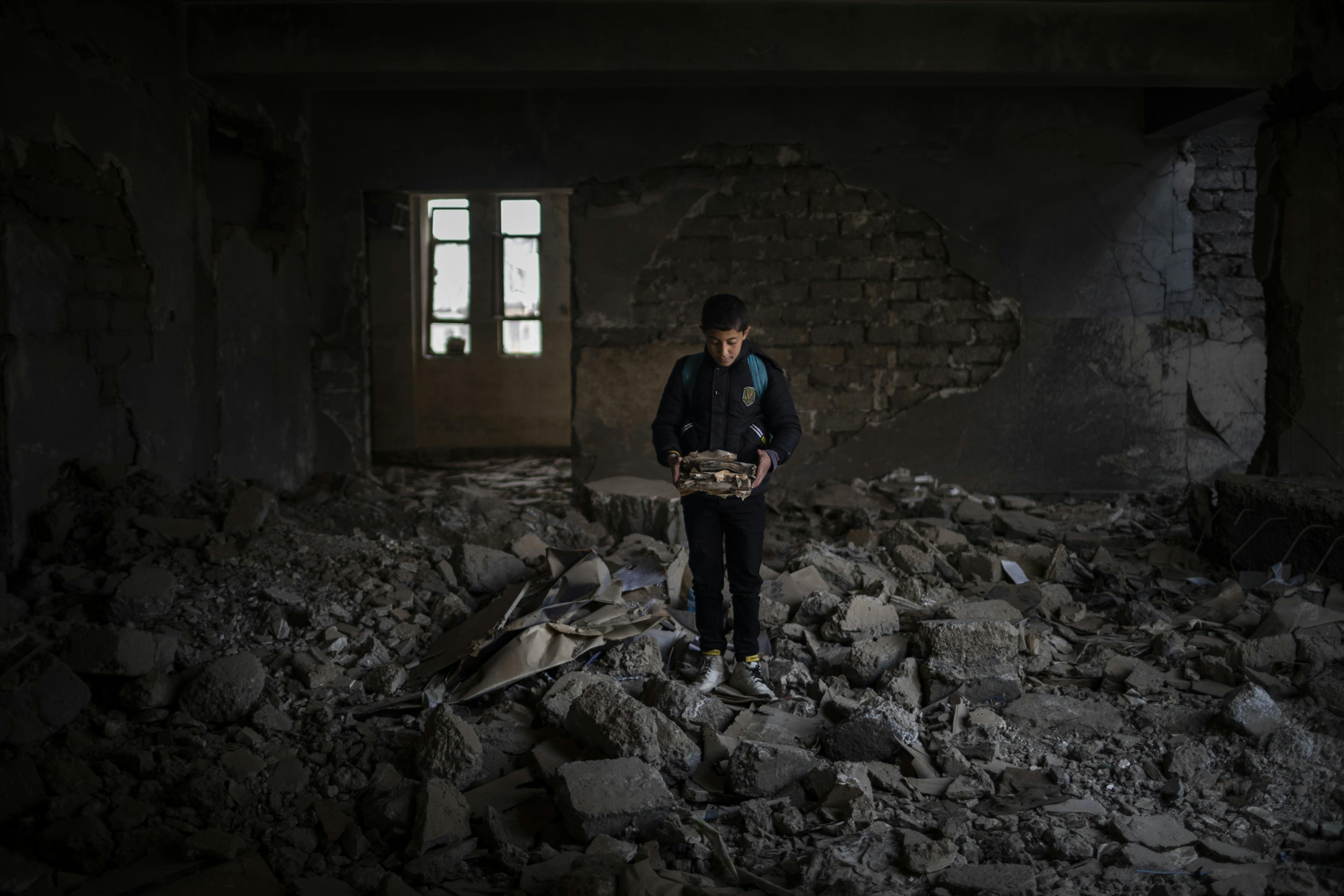 12-year-old Yousef holds destroyed books at Jummuria Secondary School. Yousef dreams of becoming a police officer. The school was severely damaged by shelling during the war in Mosul.