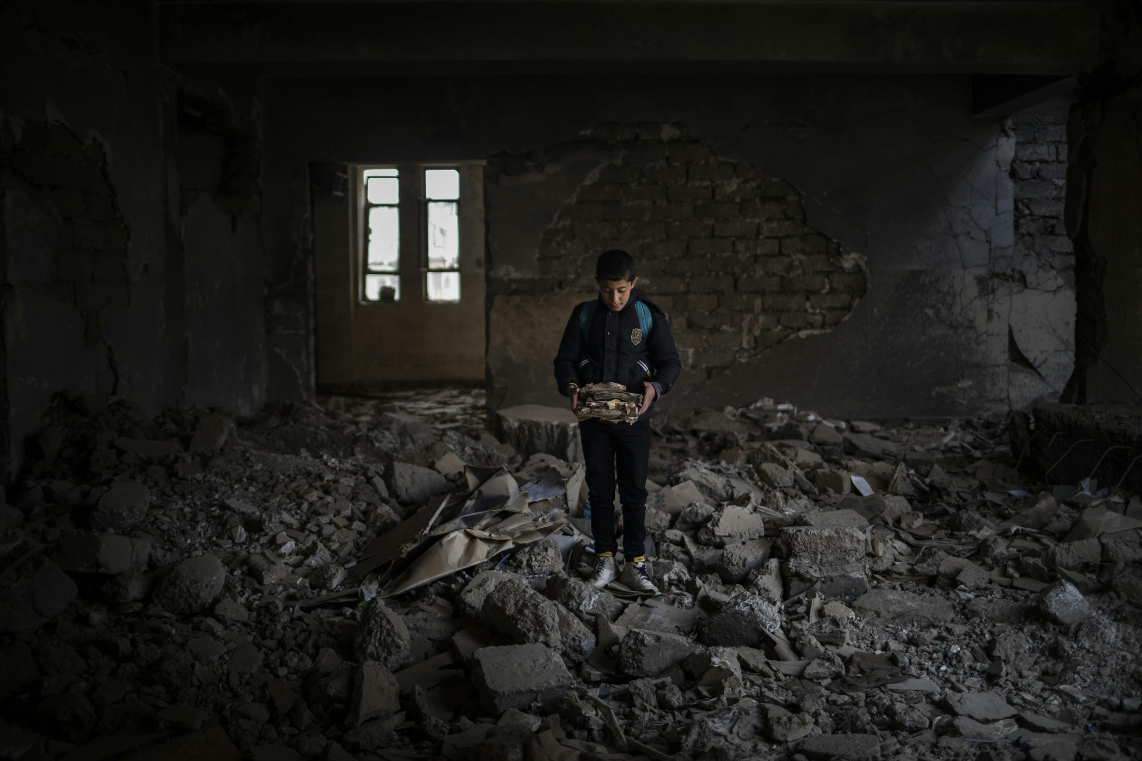  12-year-old Yousef holds destroyed books at Jummuria Secondary School. Yousef dreams of becoming a police officer. The school was severely damaged by shelling during the war in Mosul.
