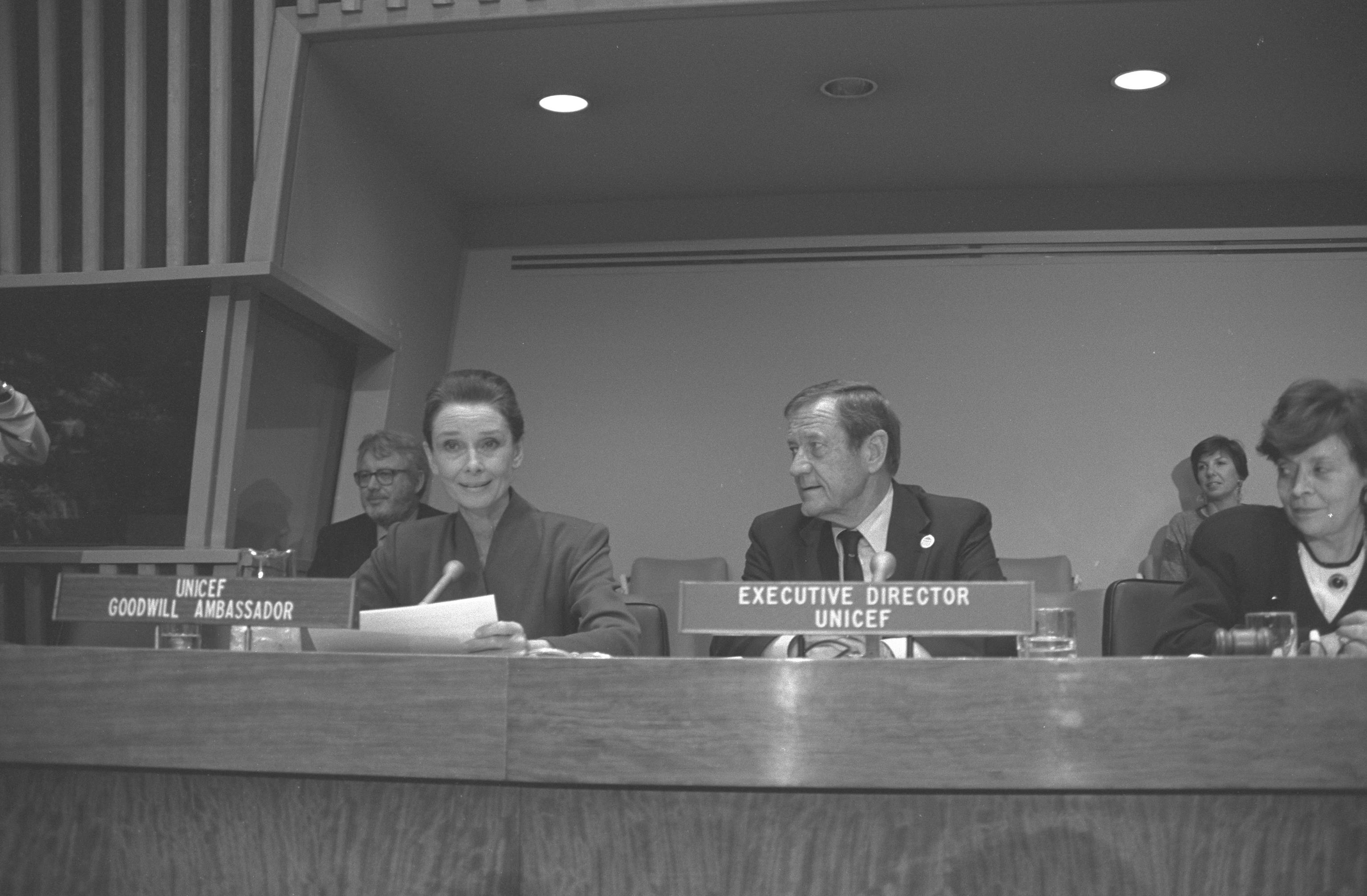 UNICEF Goodwill Ambassador Audrey Hepburn reads an excerpt of the Convention on the Rights of the Child at a meeting with children from around the world that celebrated the passage of this historic document. UNICEF Executive Director James Grant is sitting next to Ms. Hepburn at the podium.