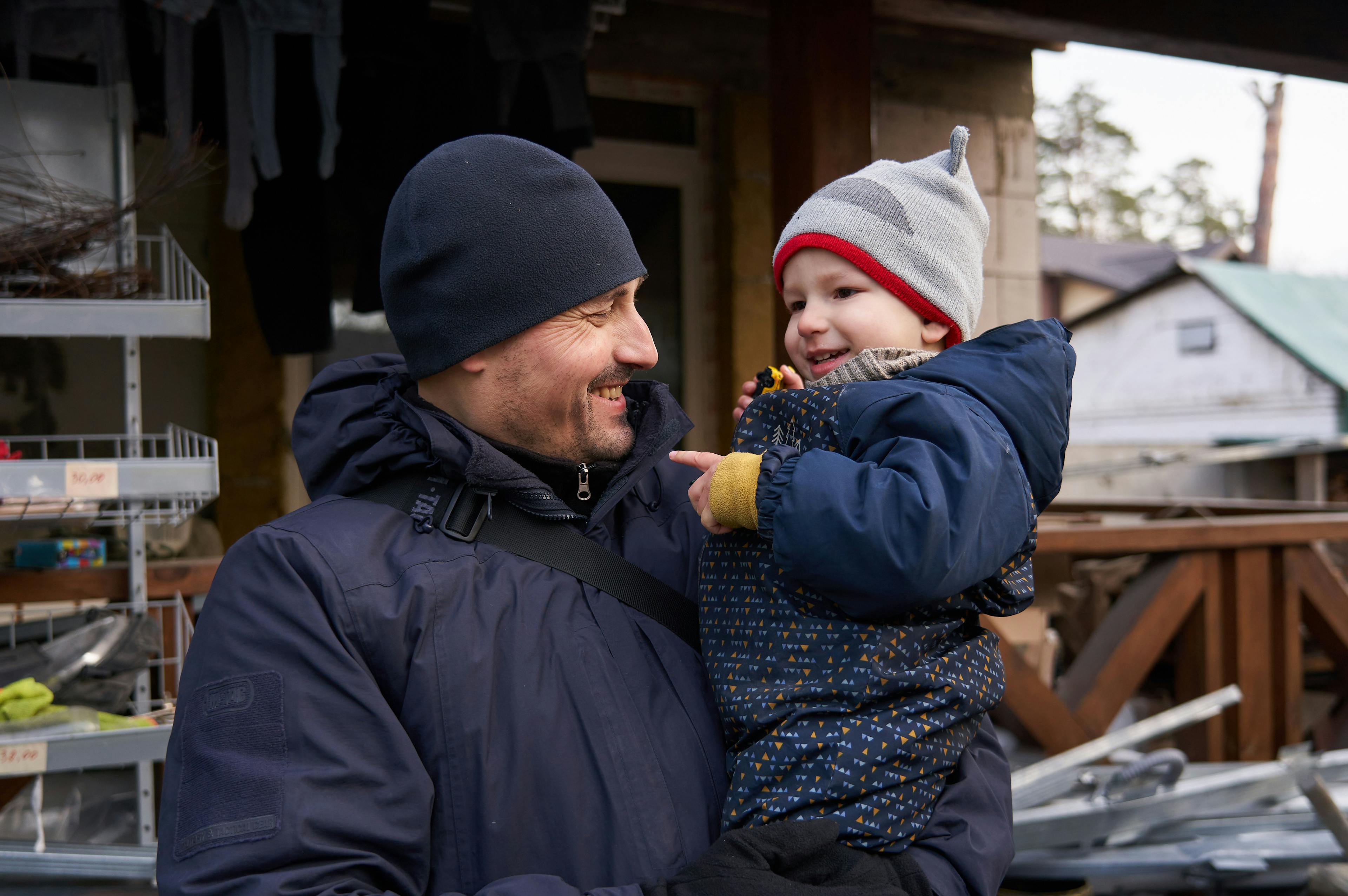 A father smiles as he holds his happy son rugged up in winter clothes