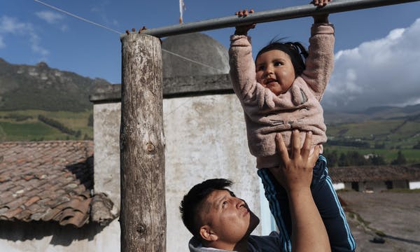 In Turugucho, Ecuador, Richard Yanez holds his 2-year-old daughter, Aysel, as she swings on a pole outside their home.