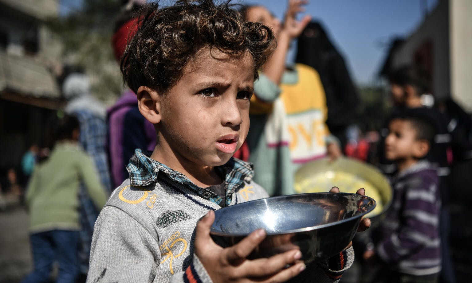 Ahmad, 5-years-old, waits his turn in the crowd to get a meal from a charitable hospice that distributes free food in the city of Rafah, southern the Gaza Strip. 
