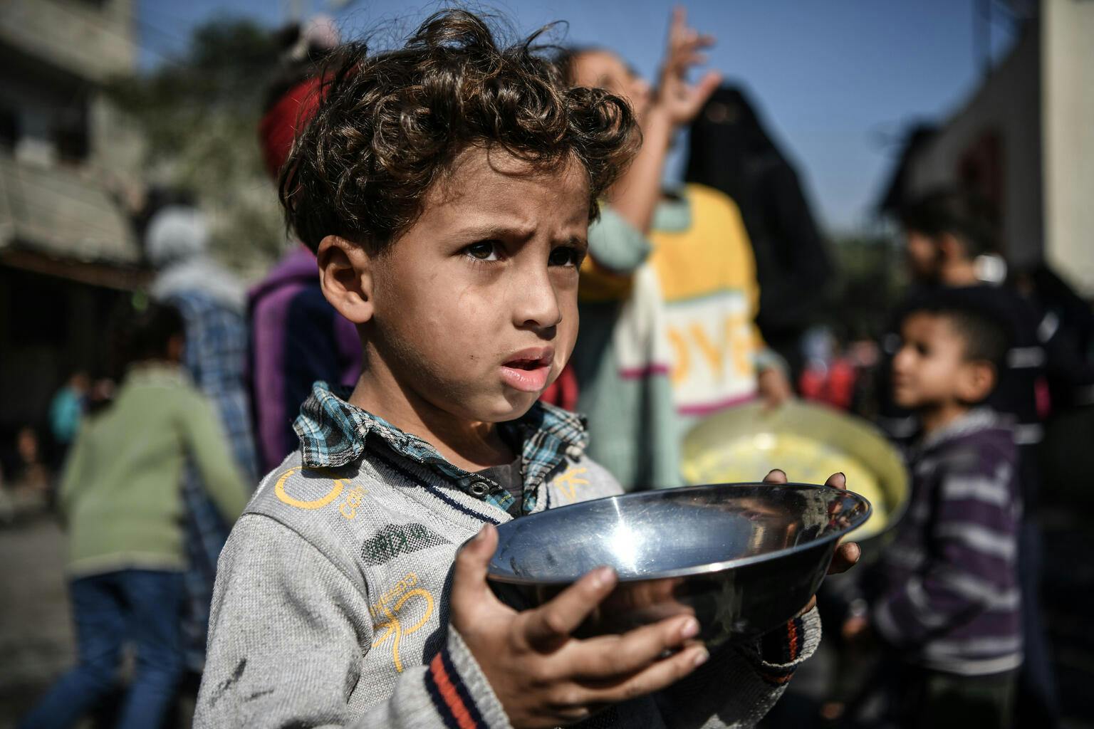 Ahmad, 5-years-old, waits his turn in the crowd to get a meal from a charitable hospice that distributes free food in the city of Rafah, southern the Gaza Strip.