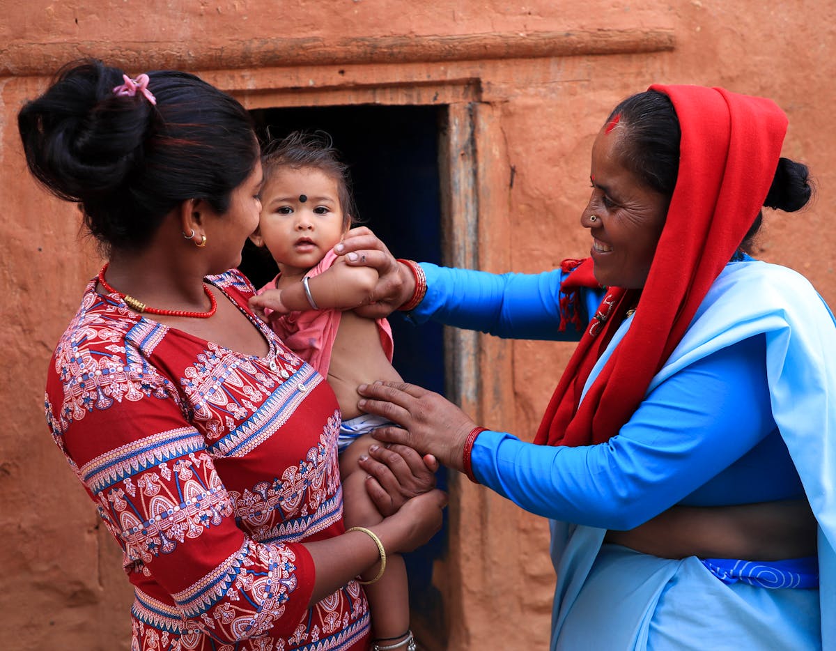 Health & Medicine- Female Community Health Volunteer (FCHV) Sharada Madai (right) interacts with Nitu Nepali and one-year-old Nitika in their home in the Jorayal Rural Municipality in Doti District in far-western Nepal.
