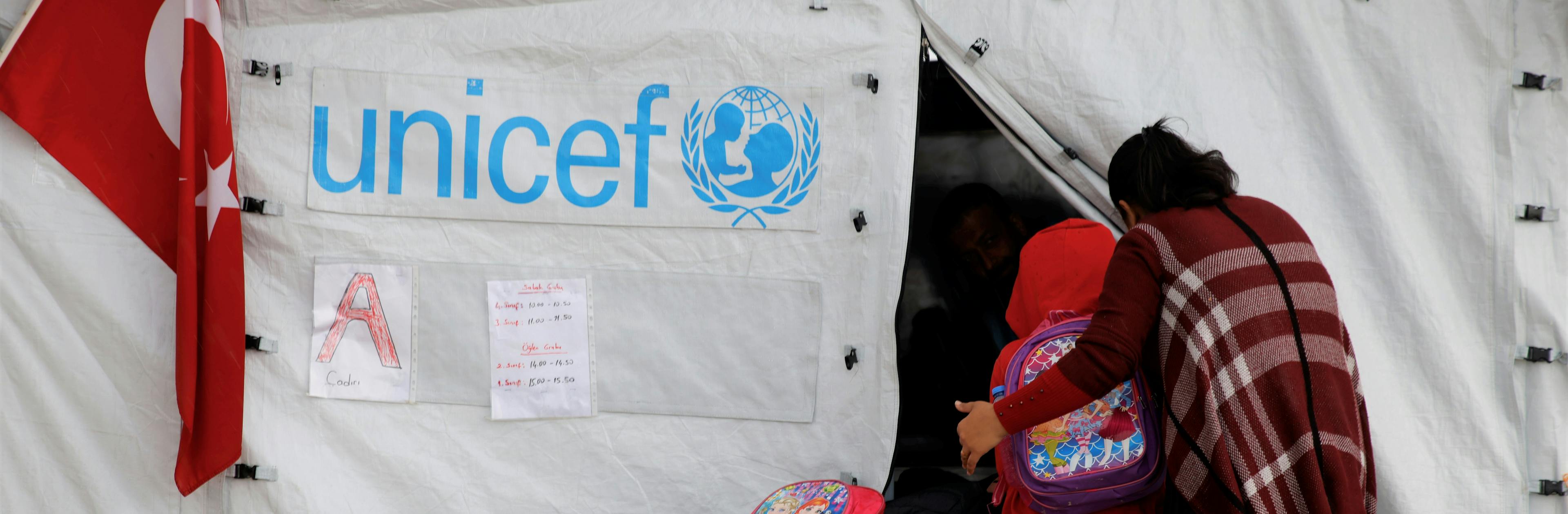 Children and a mother going into a UNICEF-supported tent classroom in a temporary shelter in Antakya, after two devastating earthquakes hit south-east Türkiye.