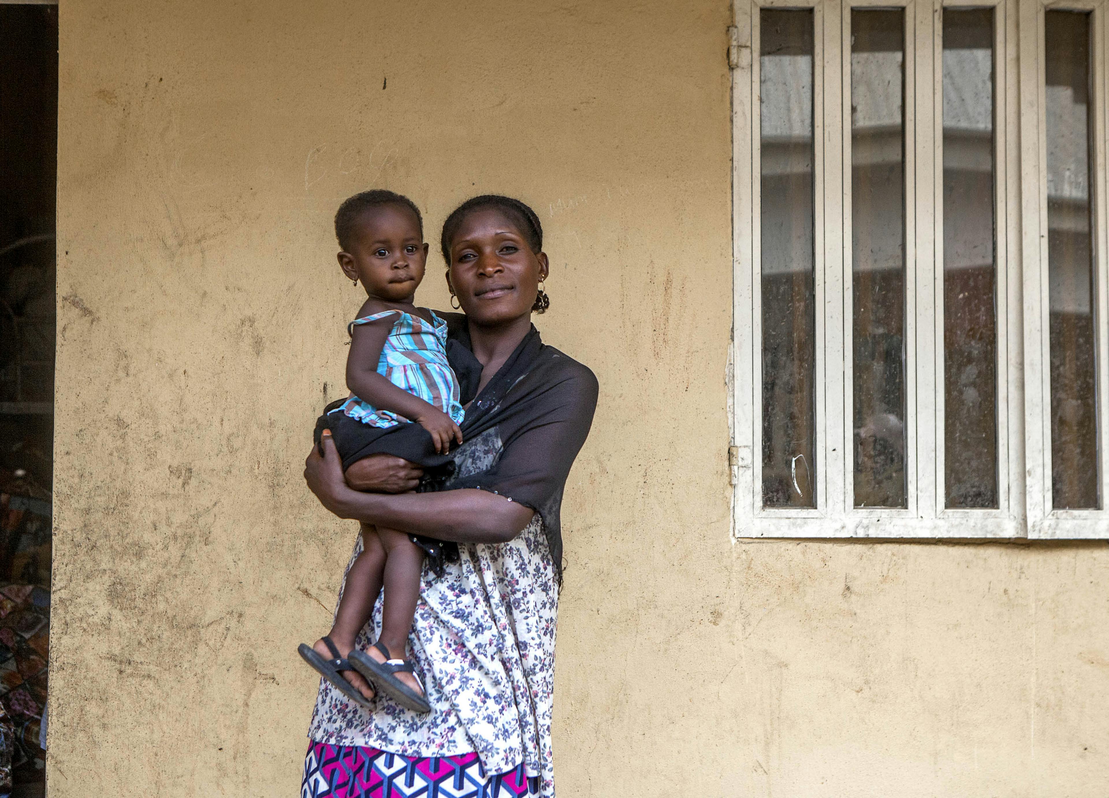 Maryamu rescued her daughter from Boko Haram. She smiles at the camera in front of their home