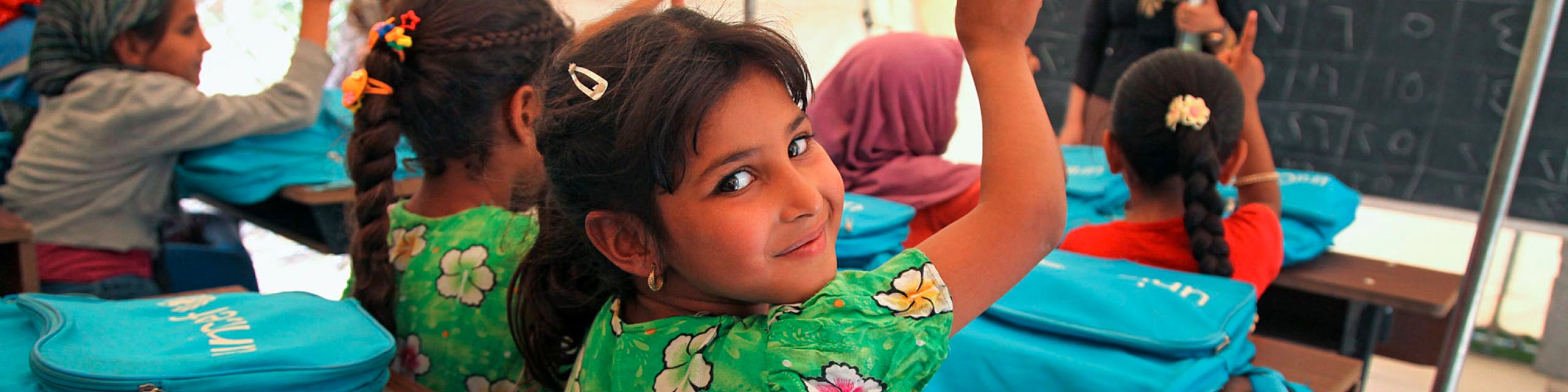 Girl in a classroom looking back over her shoulder at the camera